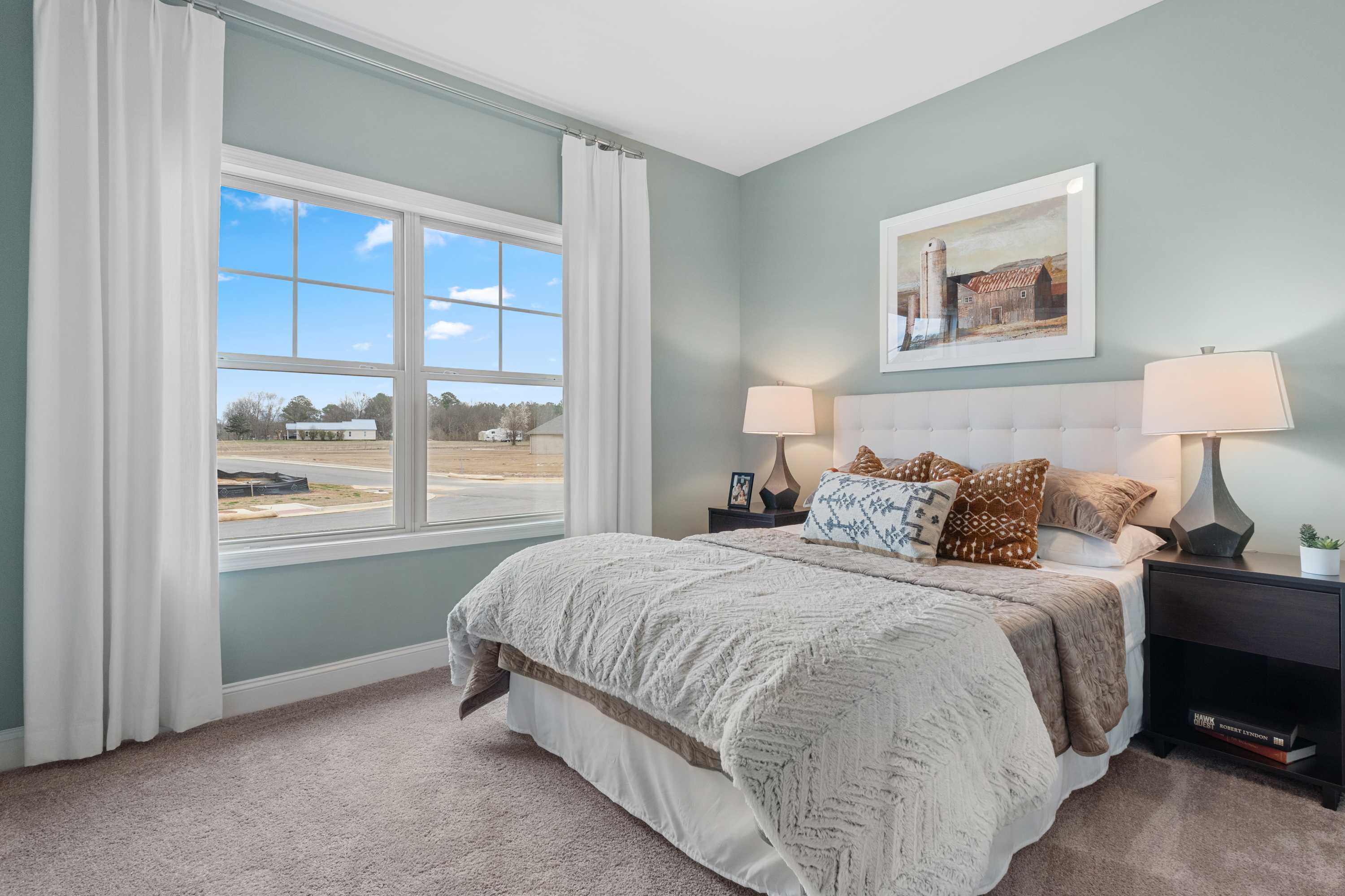 Spacious bedroom at The Retreat at Cain Park in Hartselle Alabama with large window view, tufted bed, neutral bedding, and bedside lamps