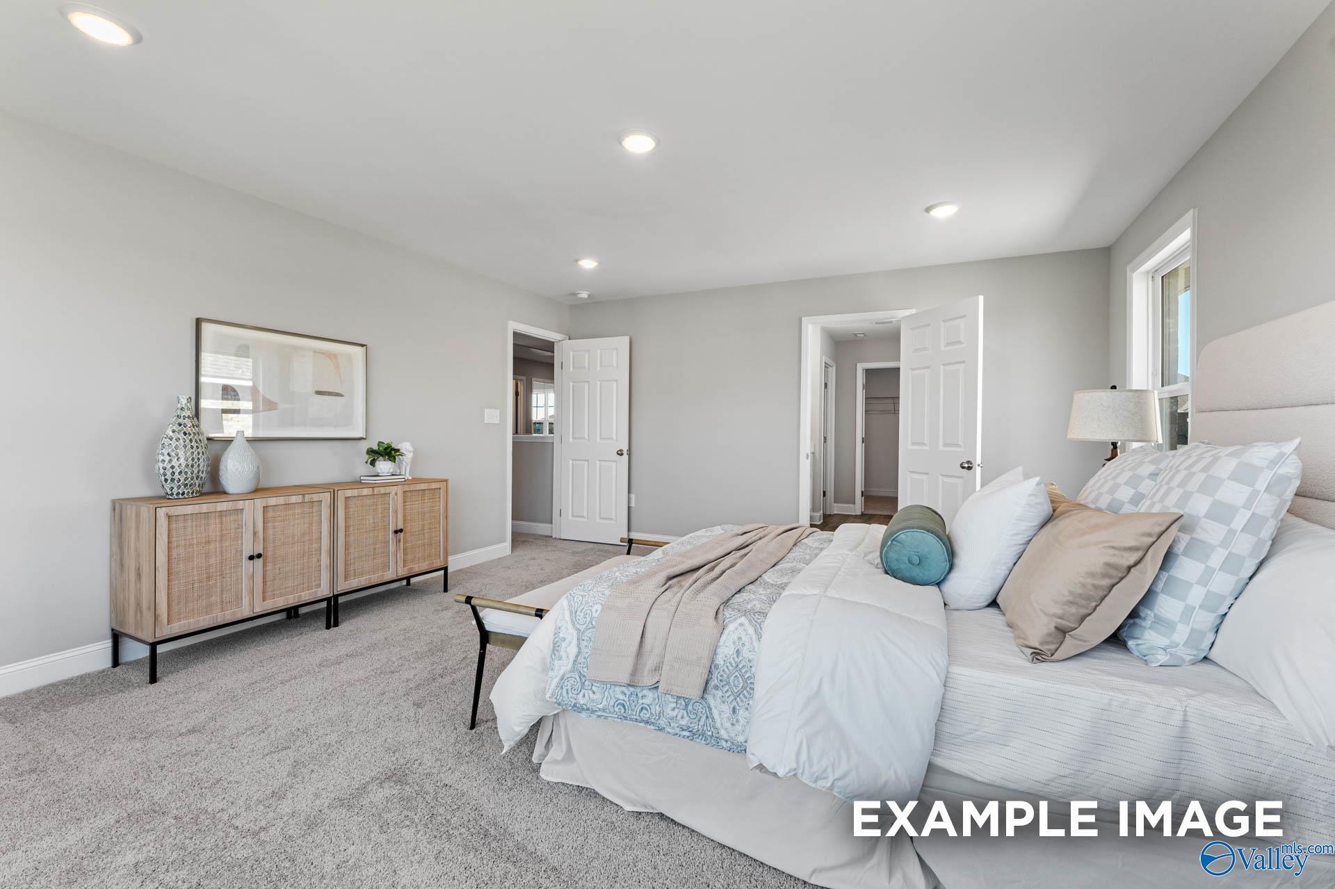Elegant master bedroom with king bed, neutral bedding, rattan dresser, closet and bath access in Davidson Homes Chelsea B, Toney AL