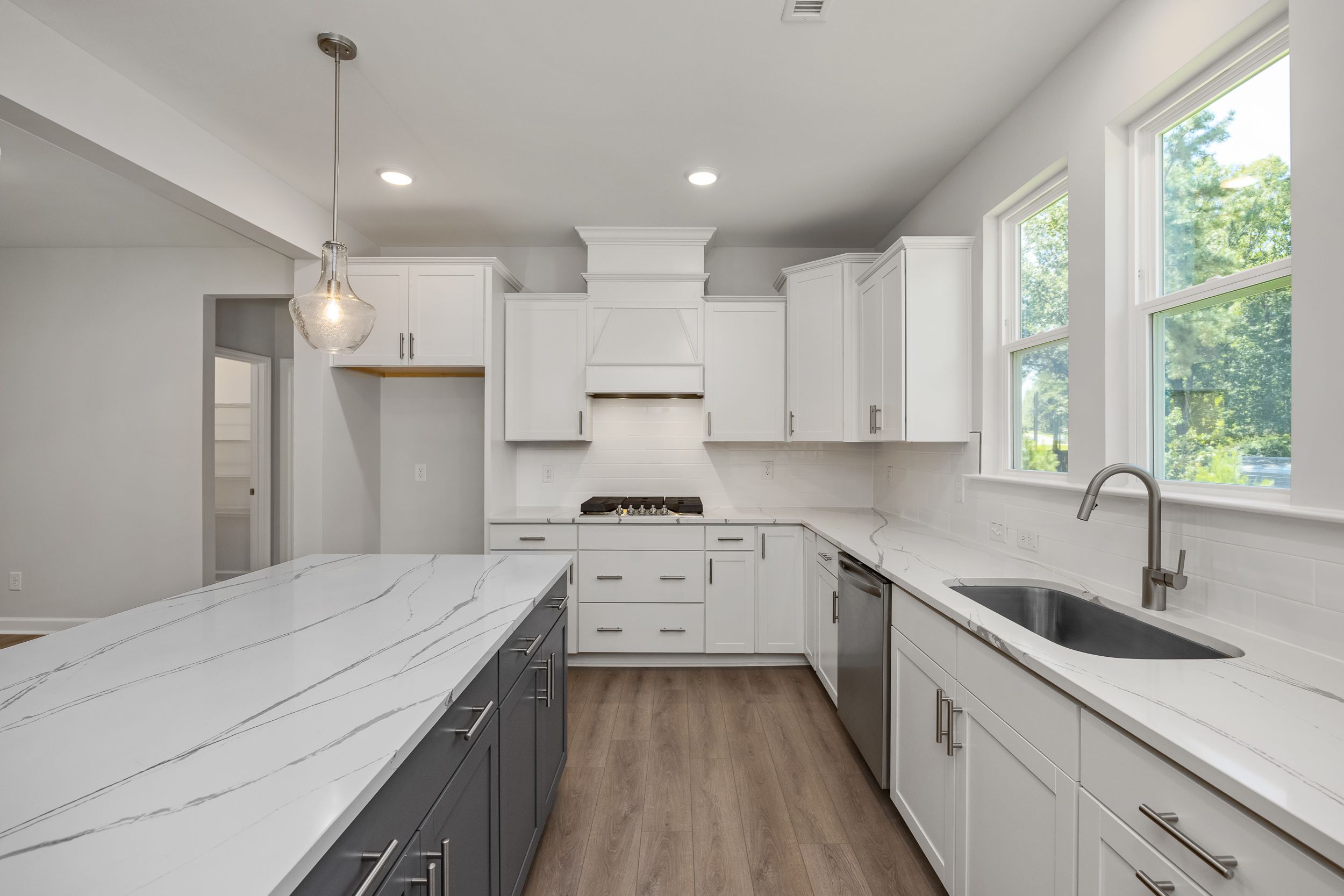 Spacious modern kitchen in The Aspen C featuring white shaker cabinets, quartz island, gas range, and large windows