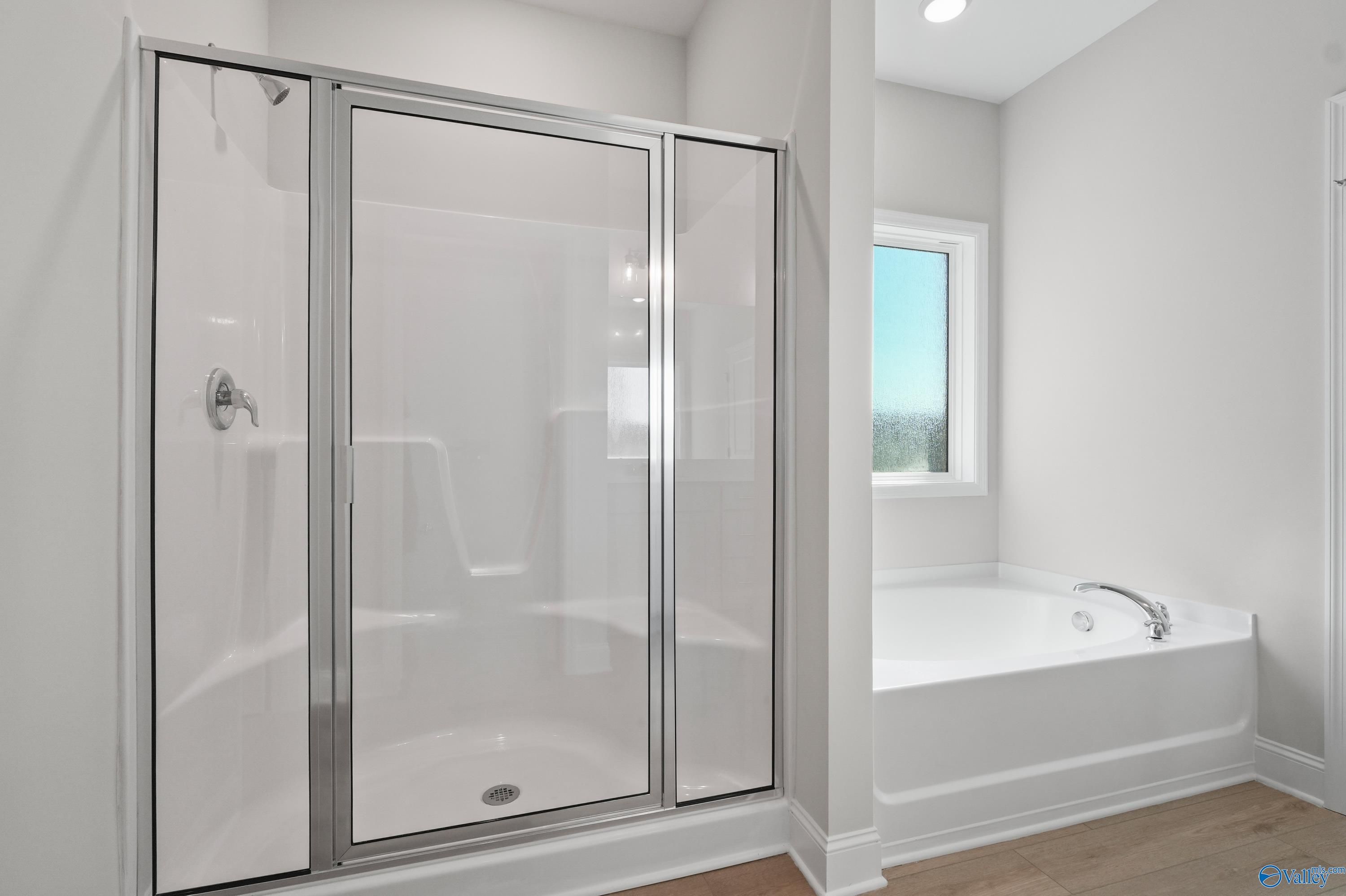 Modern master bathroom featuring frameless glass shower and soaking tub in Davidson Homes The Everett, Hazel Green, Alabama