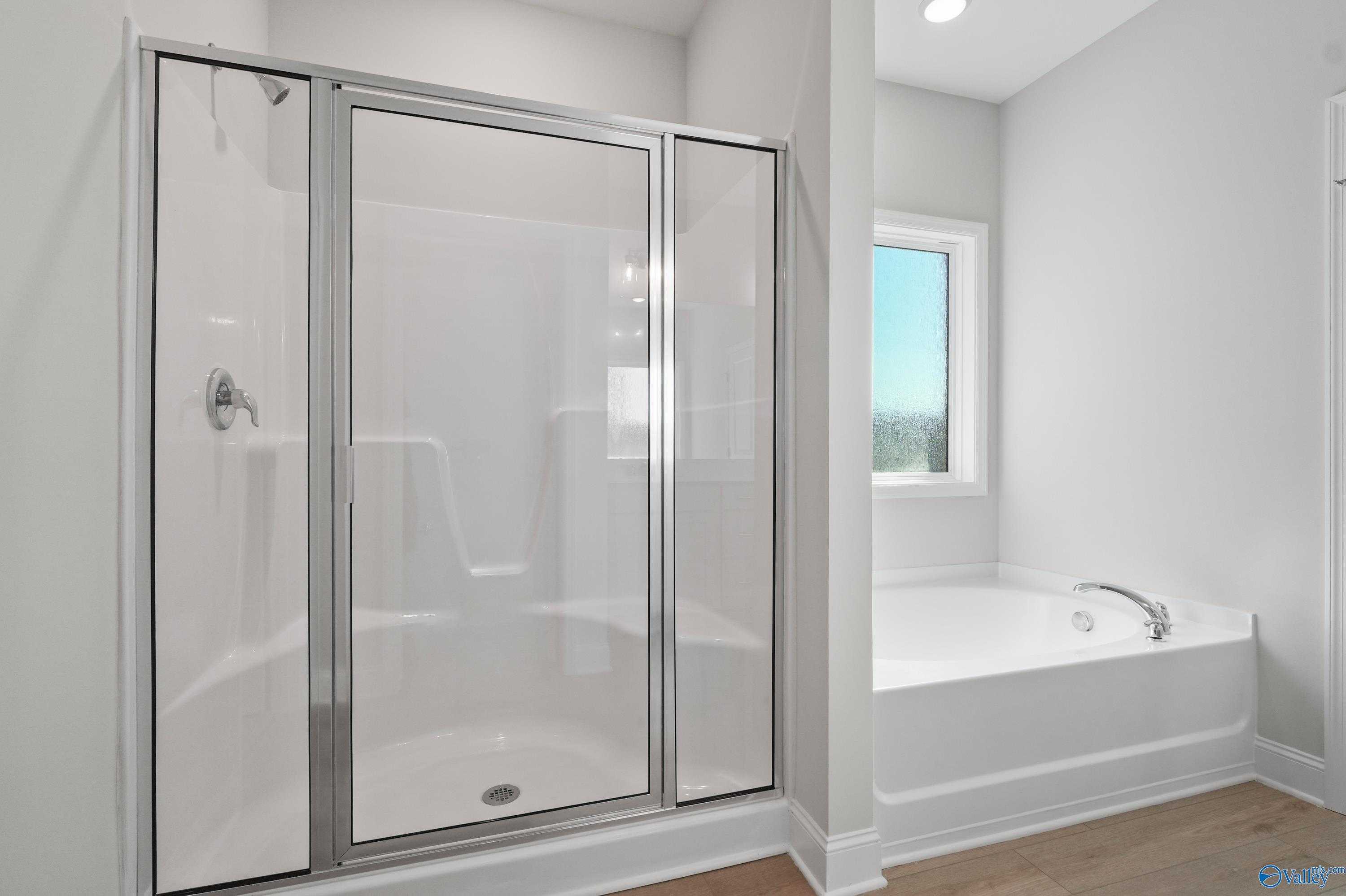 Modern master bathroom featuring frameless glass shower and soaking tub in Davidson Homes The Everett, Hazel Green, Alabama
