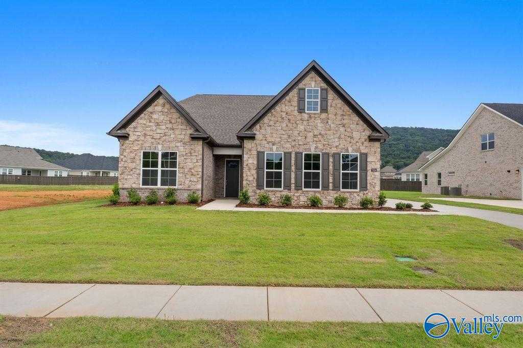Modern stone-brick 1.5-story Evermore Homes Oxford with 2-car garage, green lawn, and driveway in The Meadows at Hampton Cove, Owens Cross Roads, AL