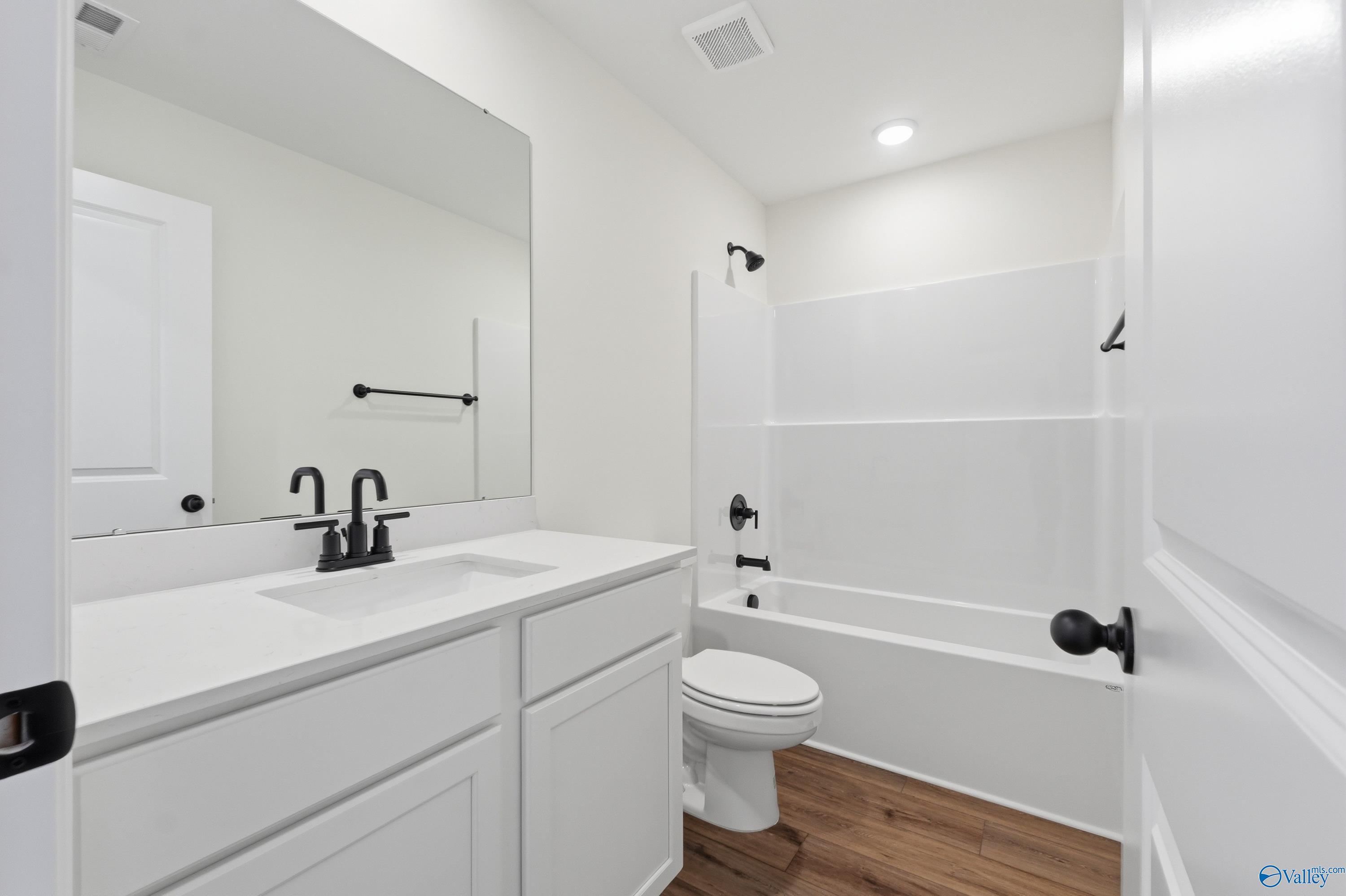 Modern bathroom with white vanity, shower-tub combo, and black fixtures in The Franklin floor plan, Heritage Lakes, AL.