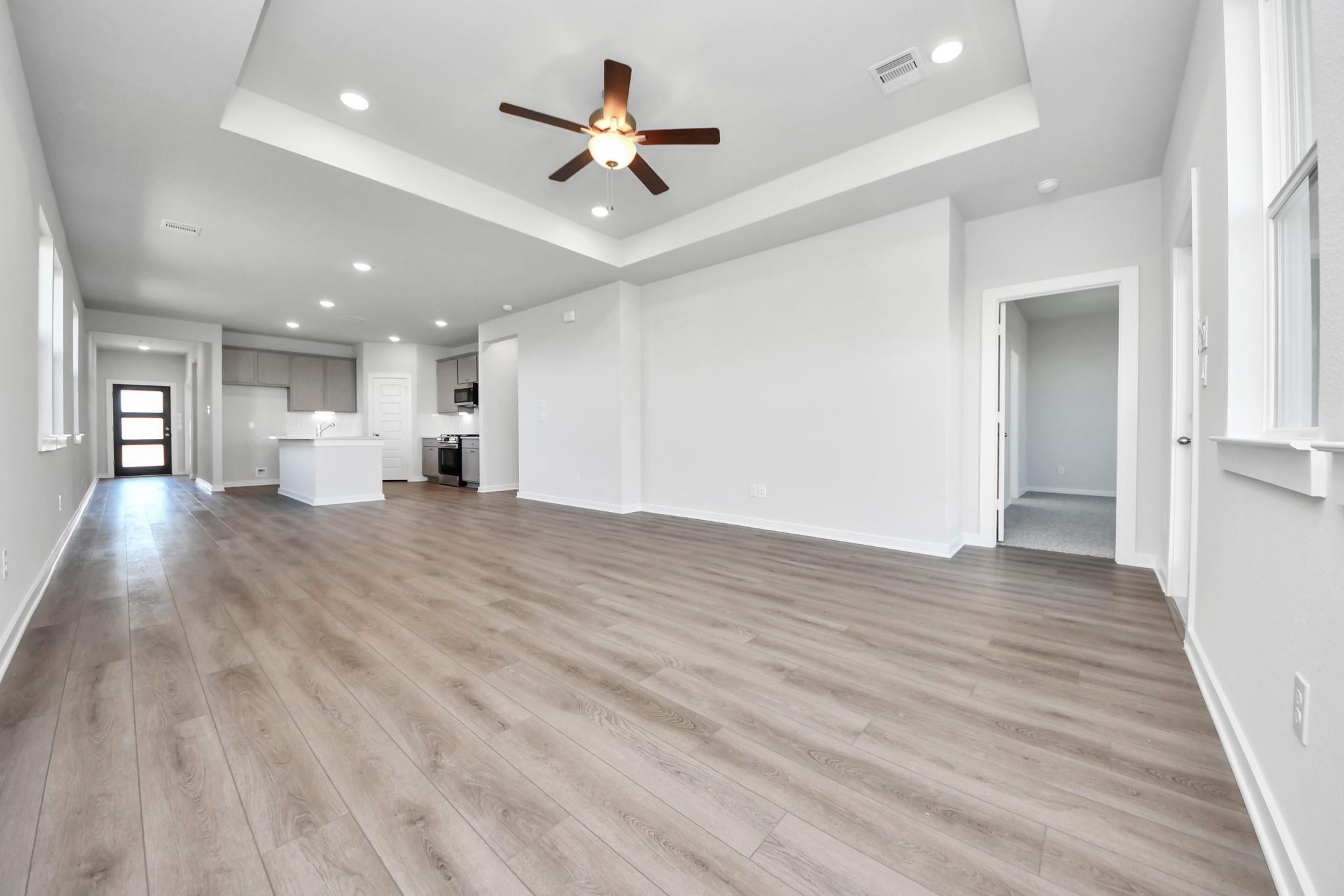 Spacious open-concept living area with tray ceiling in The Riviera A floor plan at Emberly, Beasley, Texas.