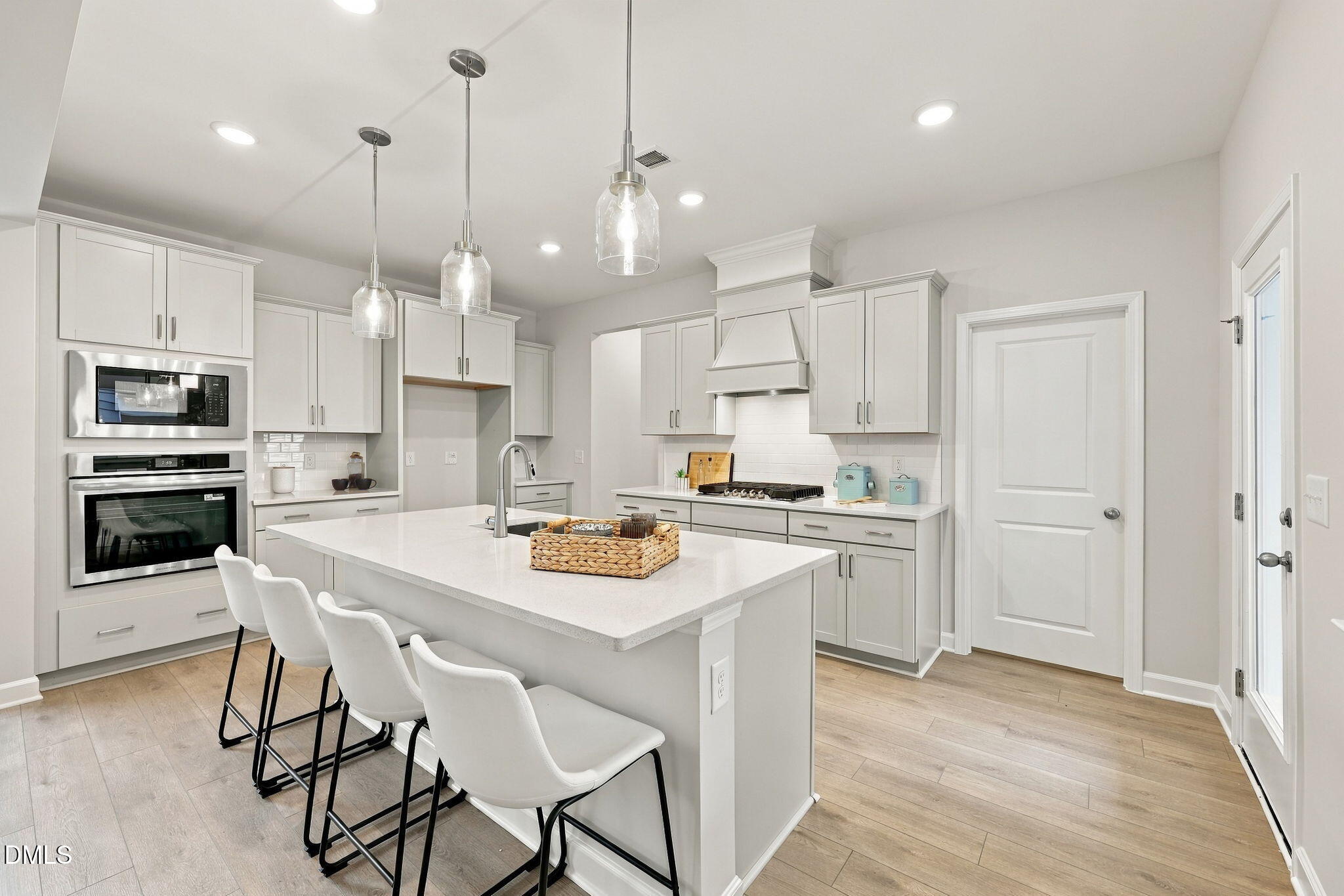 Bright white kitchen with large island, pendant lighting, stainless appliances, and bar seating in Davidson Homes The Jordan C, Knightdale NC