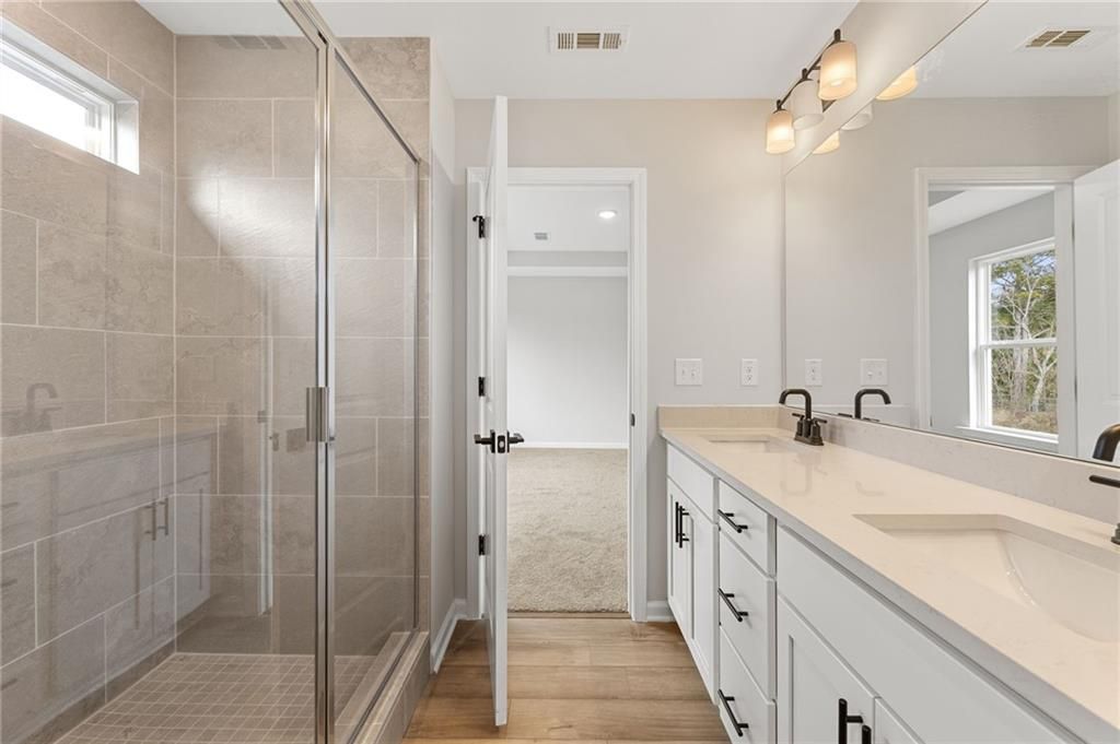 Modern master bathroom featuring open glass shower, white double vanity, quartz counters in Davidson Homes The Rabun C, Winder, Georgia