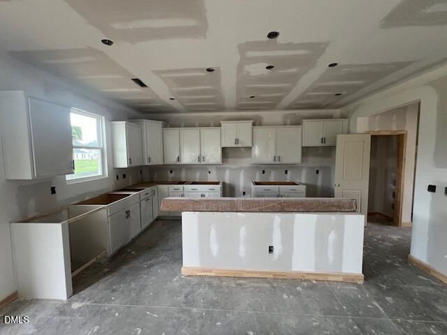 Kitchen under construction with white cabinetry and center island in The Hickory II C home, Retreat at North Main, Lillington.