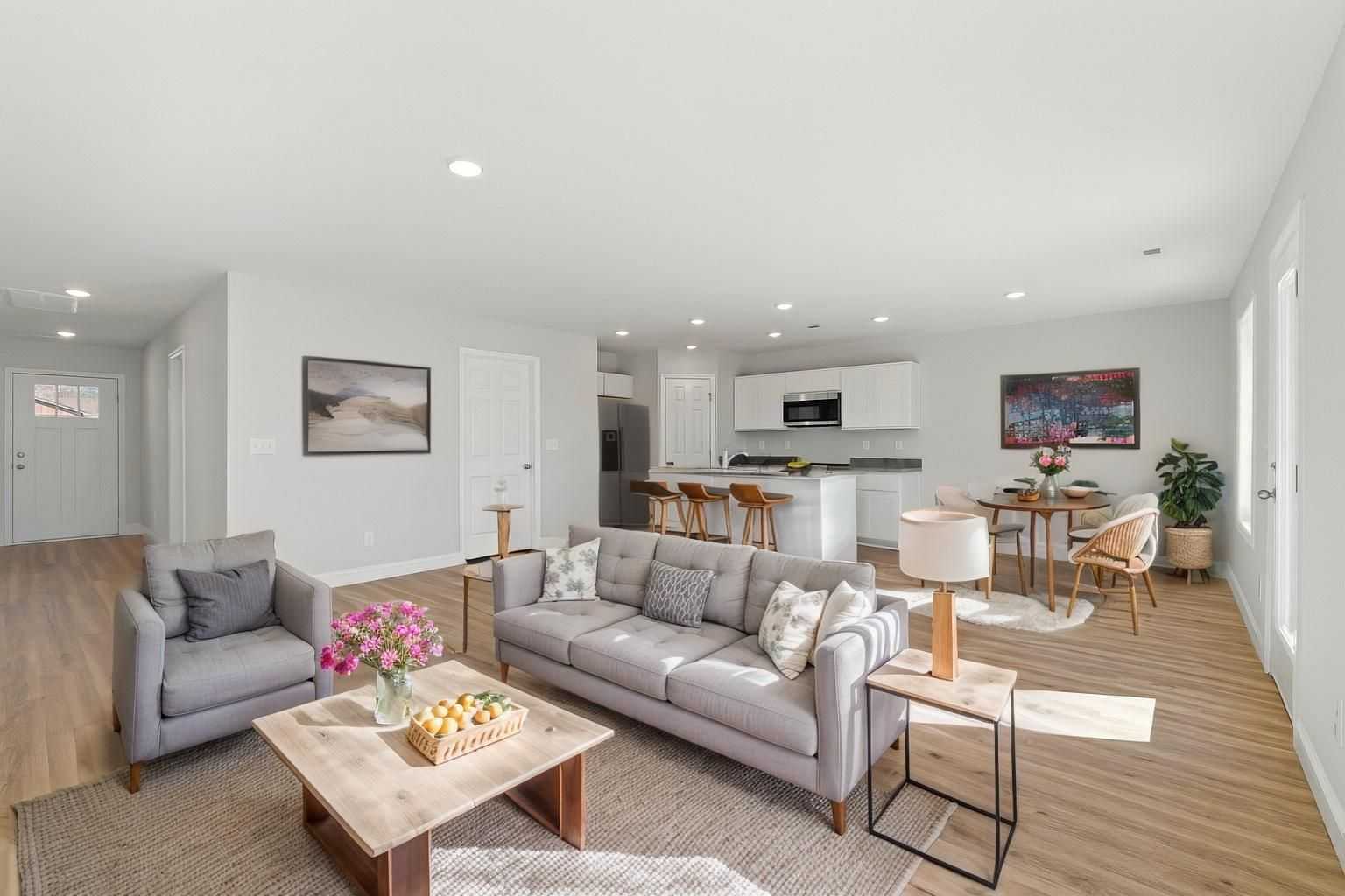 Spacious open-concept living room in Chapel Hill Athens Alabama with gray sectional sofa, hardwood floors, white kitchen island and modern artwork