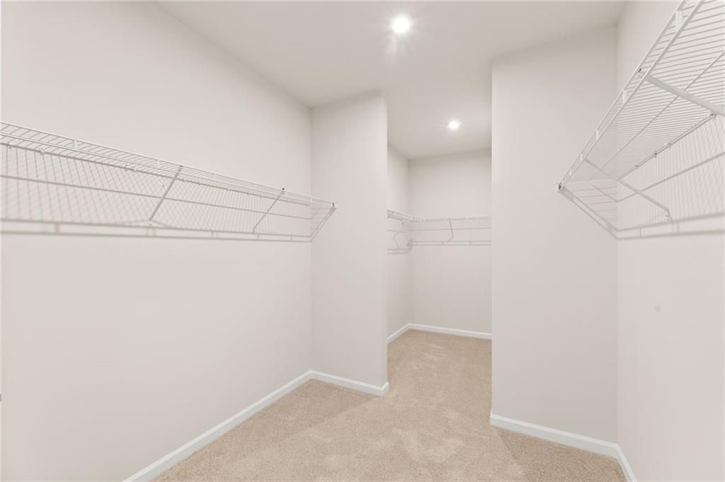 Spacious walk-in closet with wire shelving, recessed lights, and carpeted floor in Davidson Homes The Glenwood C, Loganville, GA