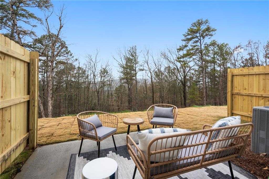 Covered back patio with wicker seating overlooking wooded backyard in Davidson Homes The Wilmington B, Emerson, Georgia