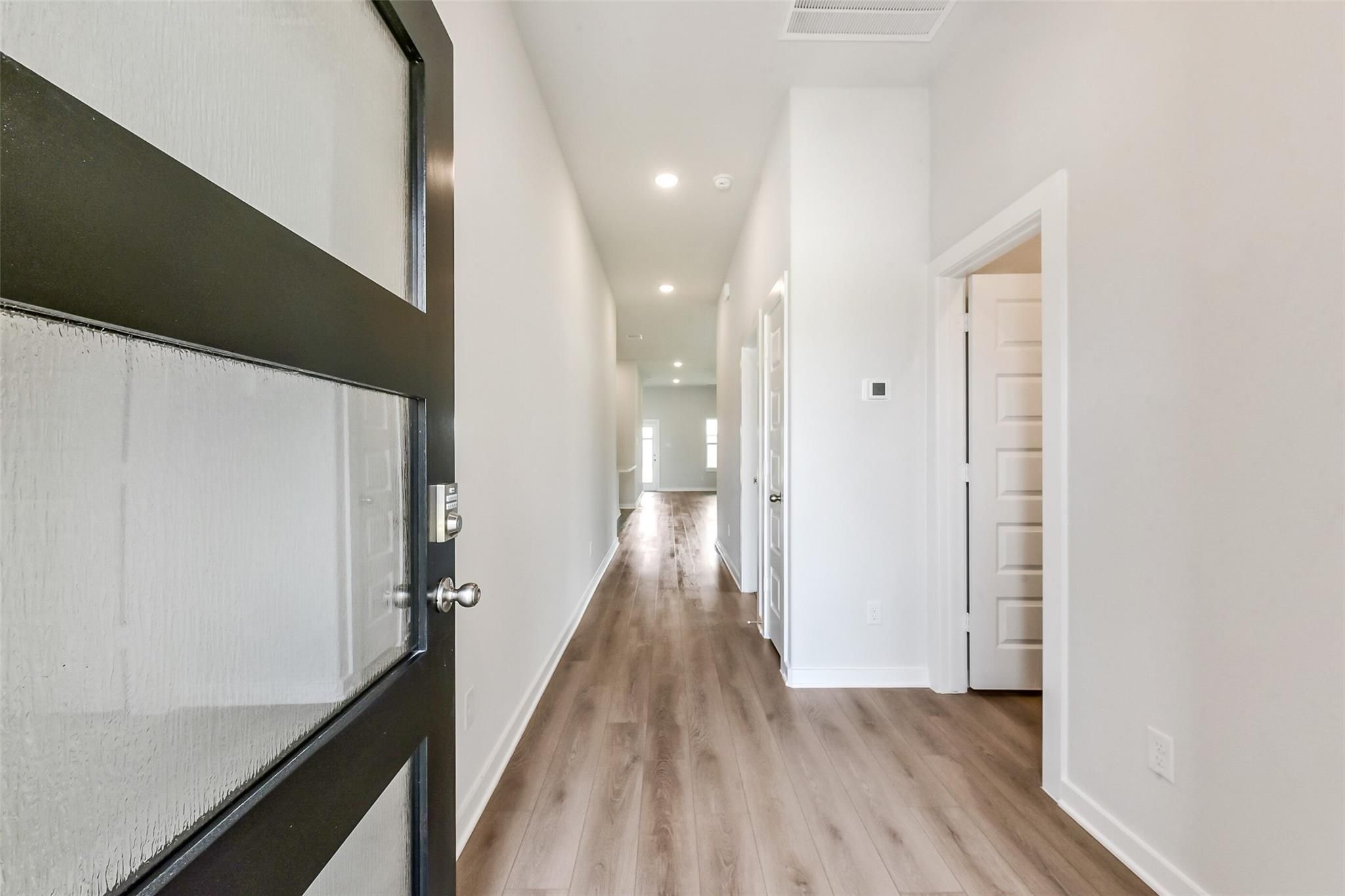 Bright entry hallway with light wood floors and white walls in 3-bedroom Davidson Homes The Laguna C, Sierra Vista, Rosharon Texas