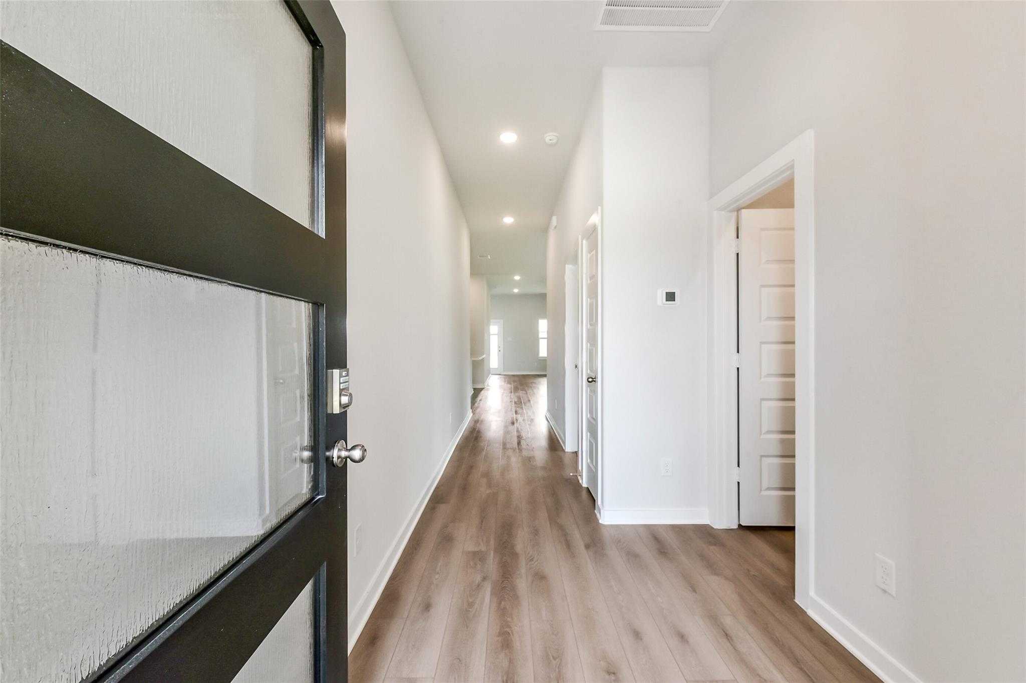 Bright entry hallway with light wood floors and white walls in 3-bedroom Davidson Homes The Laguna C, Sierra Vista, Rosharon Texas