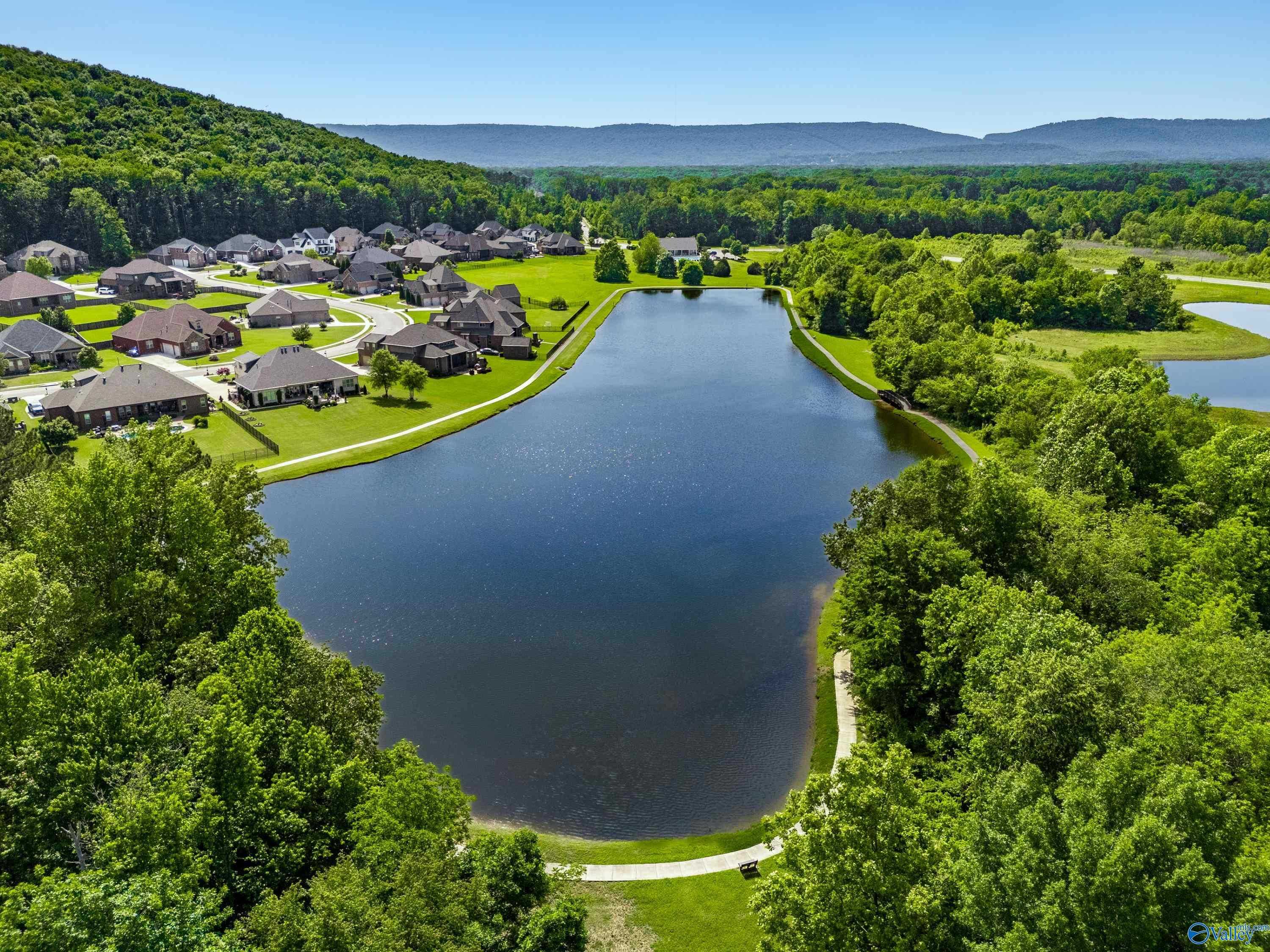 Aerial view of The Meadows at Hampton Cove with clustered homes, serene lake, walking paths, and lush greenery in Owens Cross Roads, Alabama