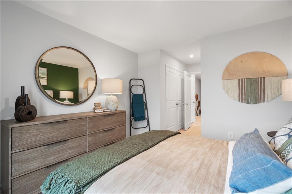 Cozy master bedroom with wooden dresser, round mirror, plush bedding in Davidson Homes The Wilmington B, Emerson, Georgia
