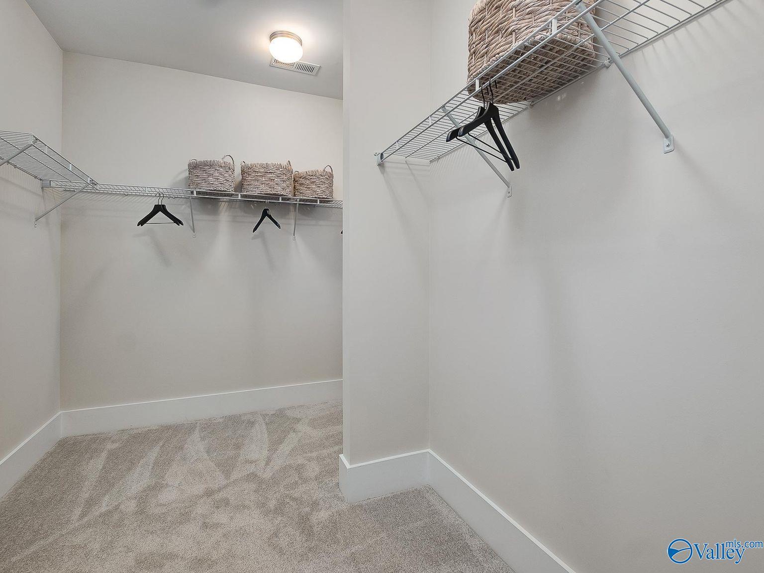 Spacious walk-in closet with wire shelving, hanging rods, and wicker baskets in Davidson Homes The Everett, Toney, Alabama