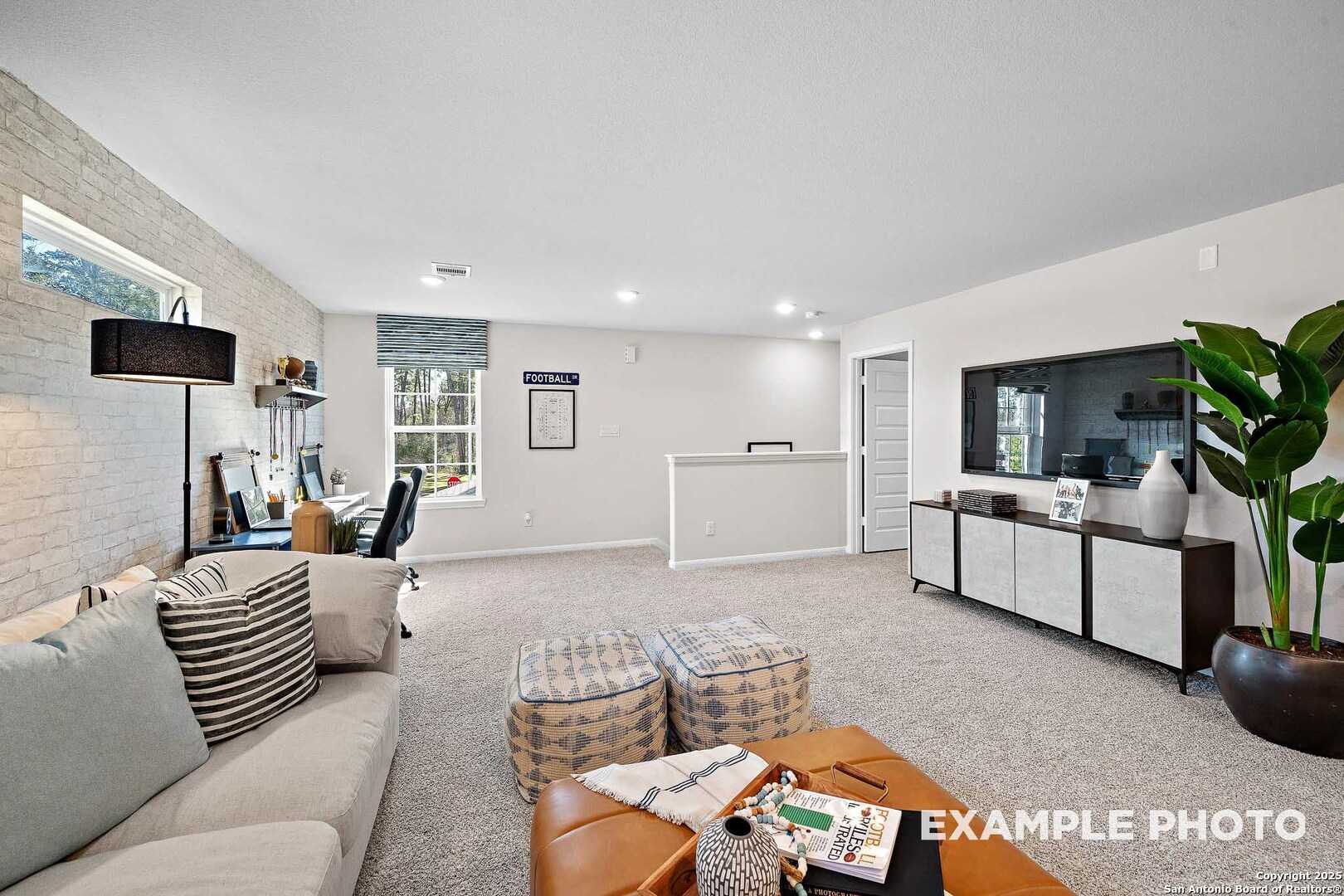 Cozy upstairs loft with beige sectional sofa, leather armchair, wall TV, and office desk in Davidson Homes San Marcos D, Agave San Antonio