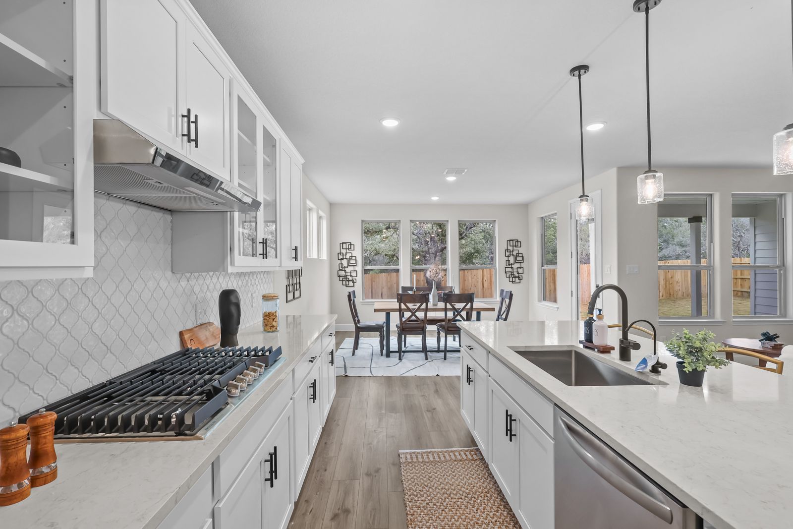 Modern kitchen in The Belmont J featuring white cabinets, quartz countertops, a large island, and an open-concept dining area.