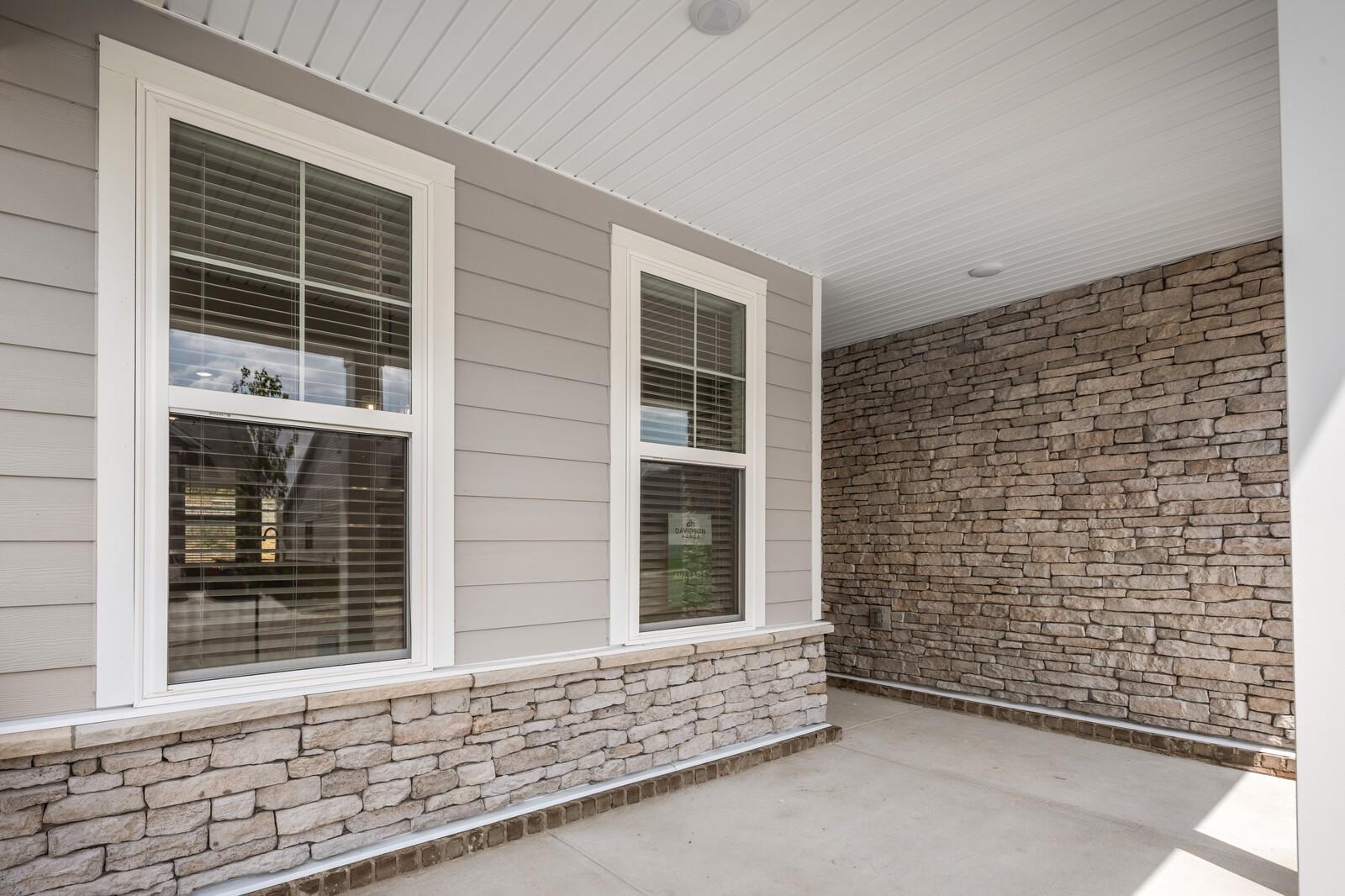 Covered front porch with stone accents and gray siding on The Willow floor plan home in Woods Crossing, Gallatin, Tennessee.