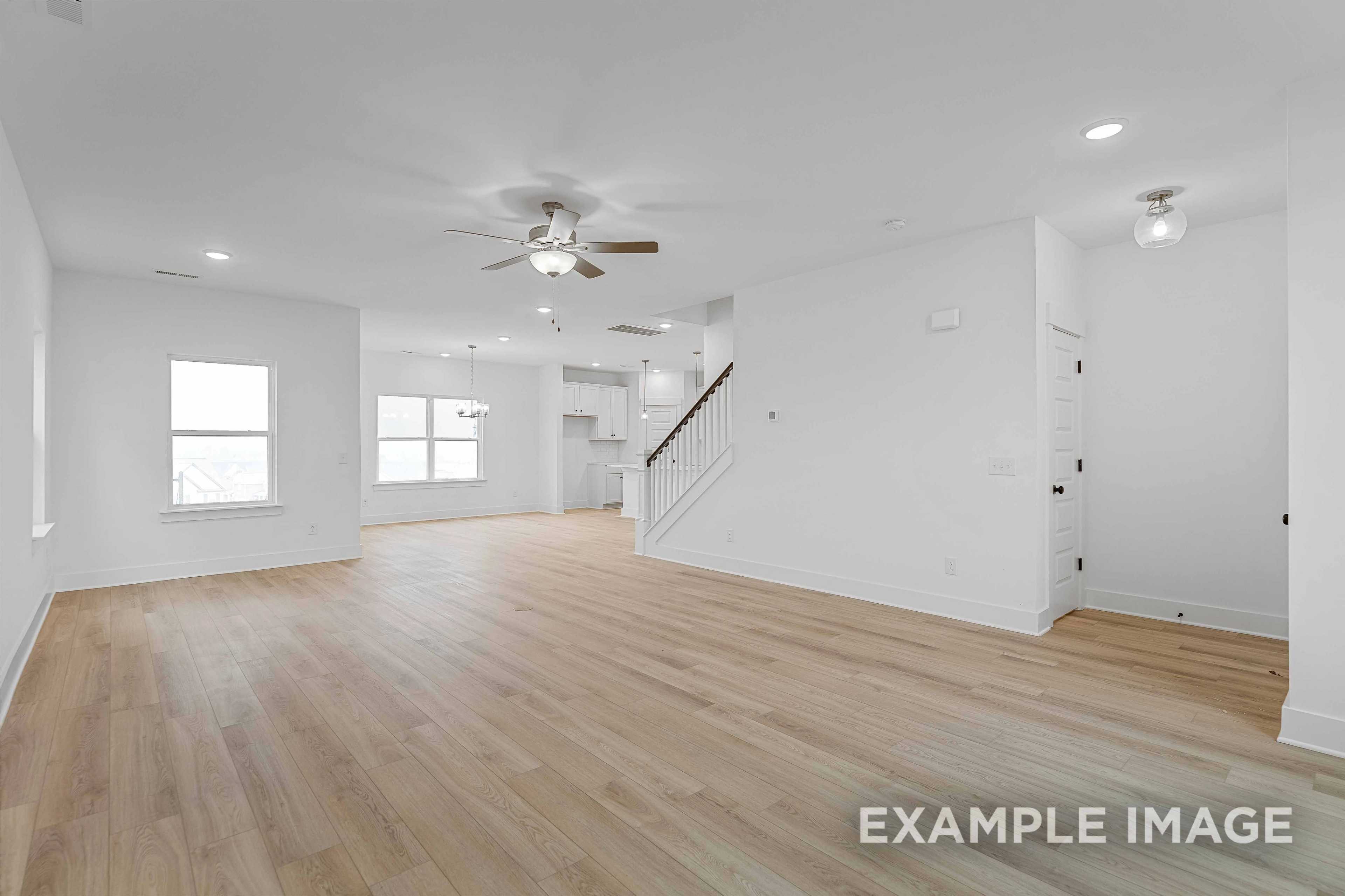 Spacious open-concept living area in The Charleston C with hardwood floors, ceiling fan, and wooden staircase