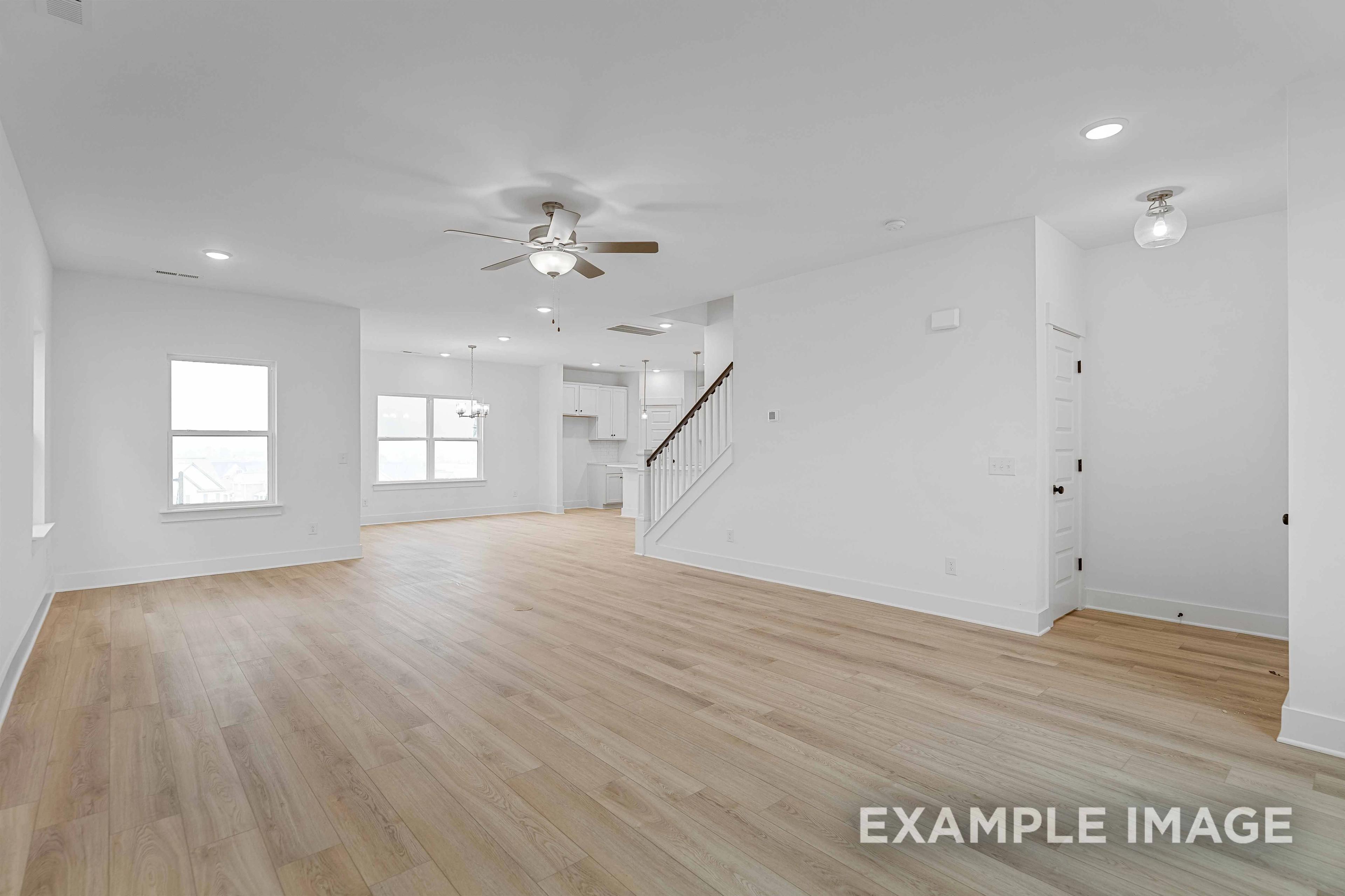 Spacious open-concept living area in The Charleston C with hardwood floors, ceiling fan, and wooden staircase