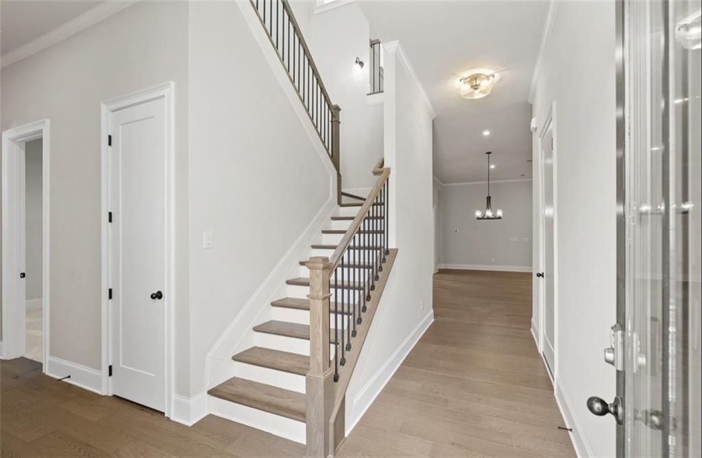 Grand wooden staircase with black metal railing and light oak floors in entry foyer of 4-bedroom Davidson Homes Seaside A, Woodstock, GA