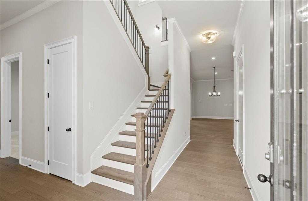 Grand wooden staircase with black metal railing and light oak floors in entry foyer of 4-bedroom Davidson Homes Seaside A, Woodstock, GA