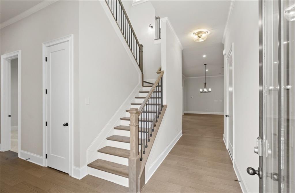 Grand wooden staircase with black metal railing and light oak floors in entry foyer of 4-bedroom Davidson Homes Seaside A, Woodstock, GA
