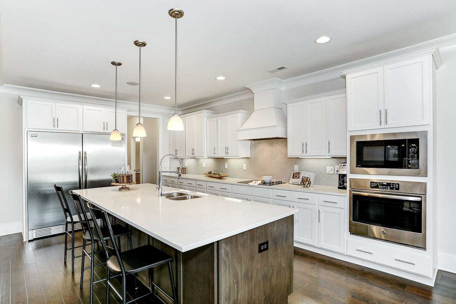 Spacious gourmet kitchen in The Finleigh with white shaker cabinets, quartz island, stainless steel appliances, and pendant lighting