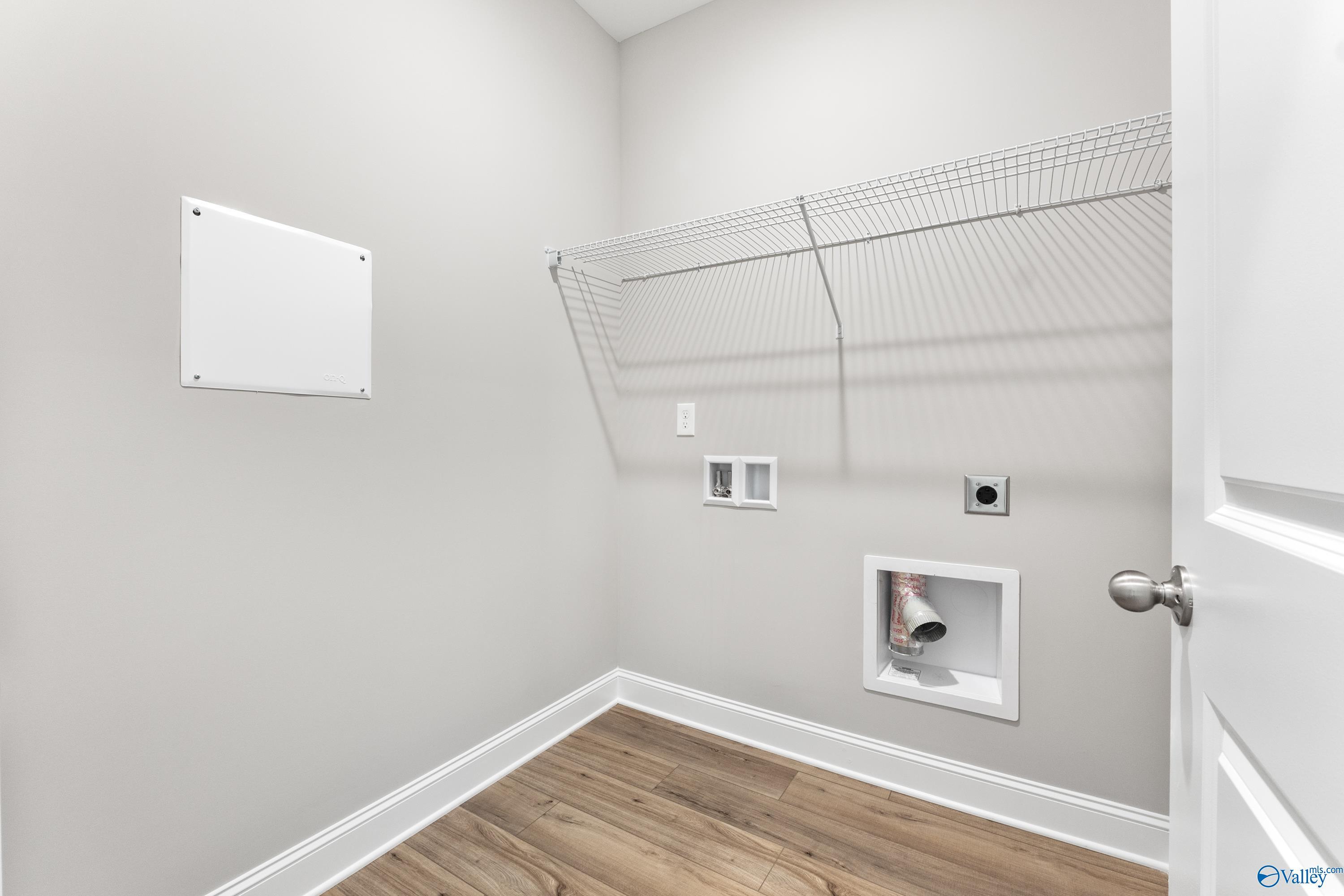 Modern laundry room with wire shelving, washer-dryer hookups, and hardwood floors in Davidson Homes The Franklin C, Huntsville AL