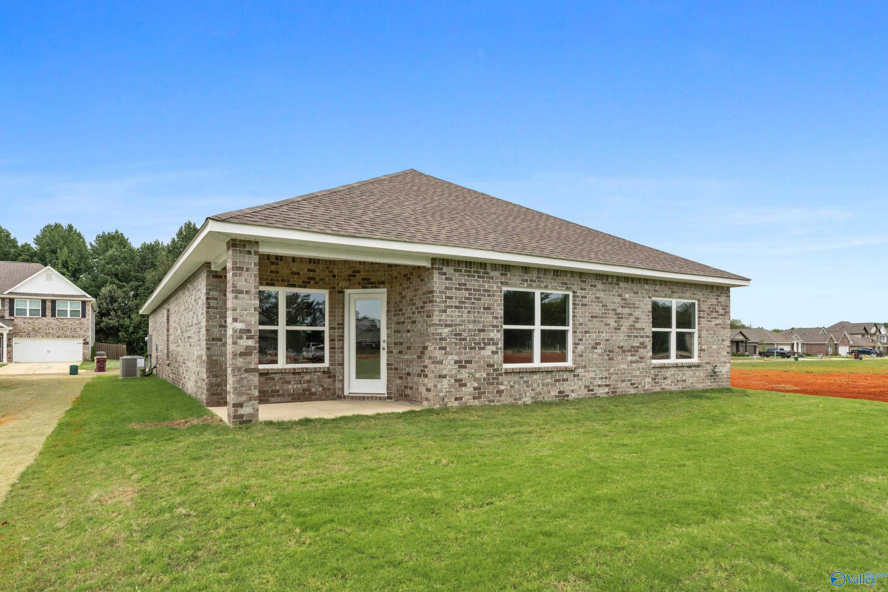Single-story brick home with gabled roof, white door, and columned porch on green lawn in Ricketts Farm, Athens, Alabama - Davidson Homes Daphne C