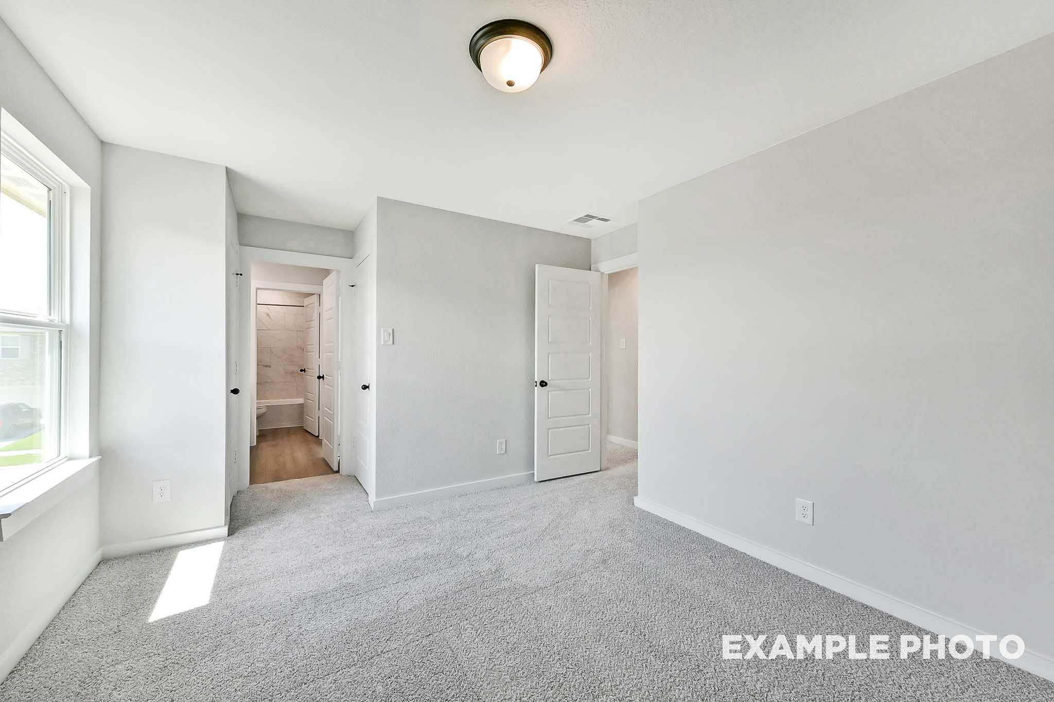 Spacious secondary bedroom in The Sequoia Davidson Homes plan with gray carpet, white walls, en-suite bath access, and natural light