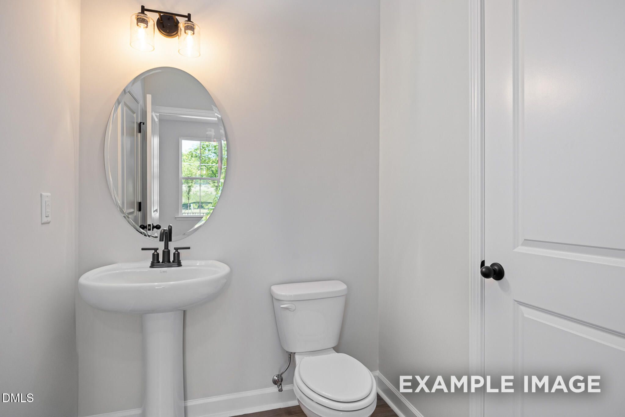 Modern powder room with pedestal sink, oval mirror, and matte black fixtures in The Mitchell floor plan at Camden Park.