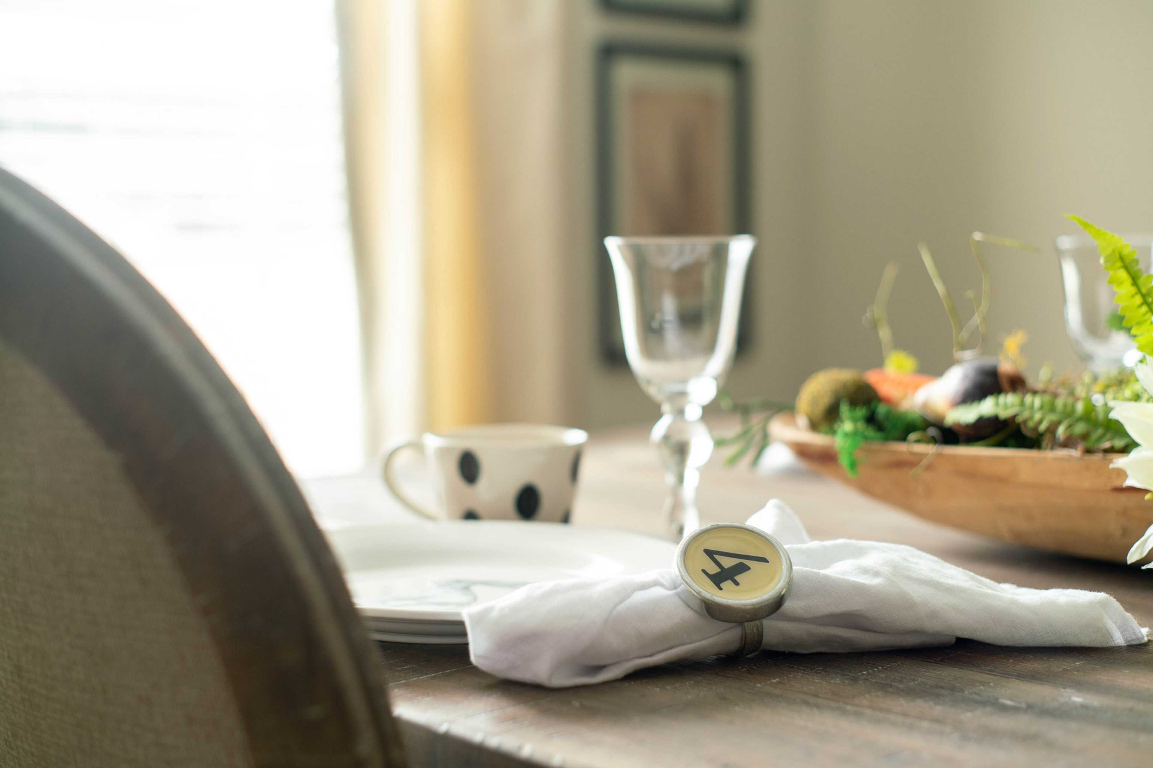 Elegant dining table at The Dairy at Oak Grove in South Huntsville AL with wooden bowl of fresh produce, wine glass, and numbered napkin ring