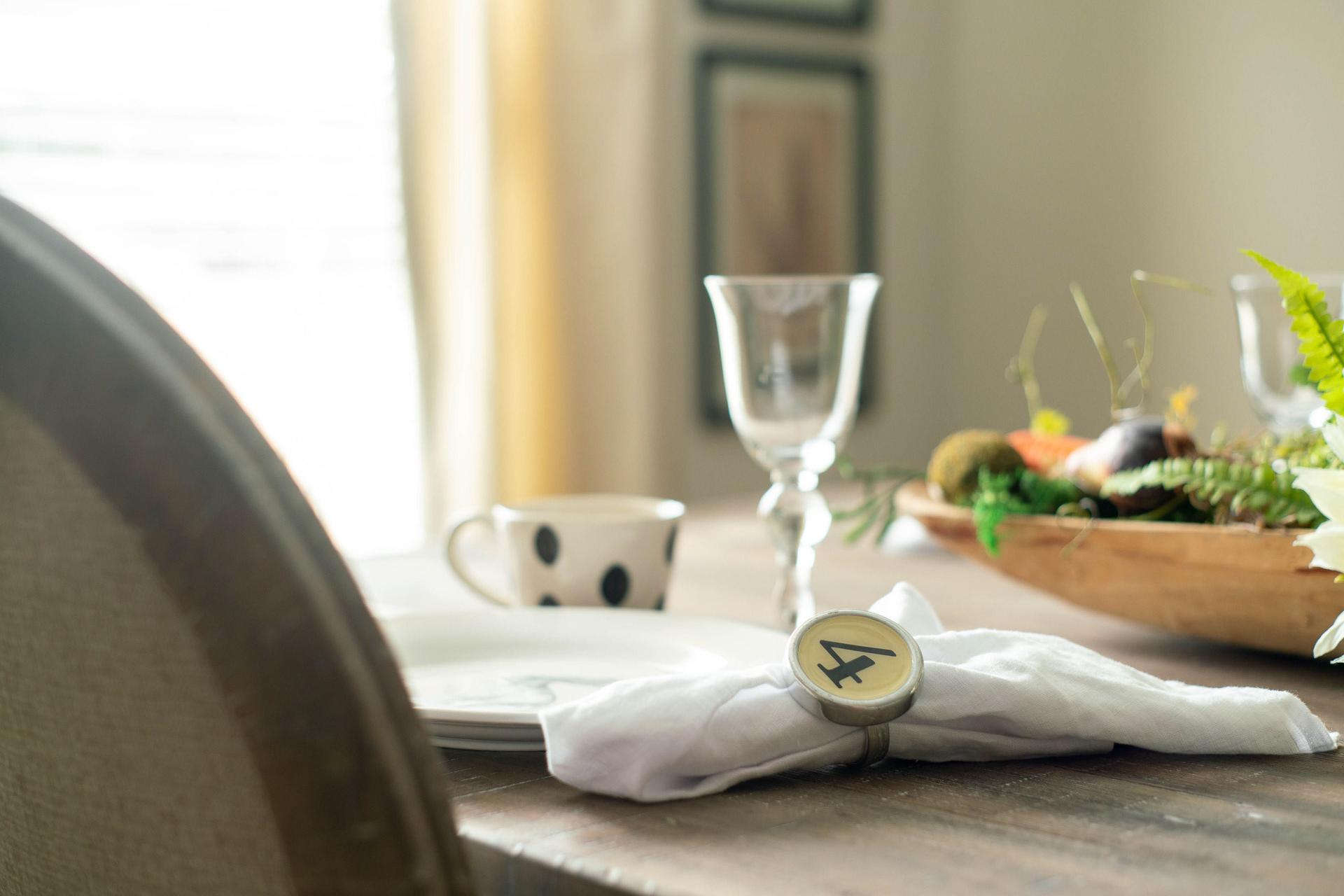 Elegant dining table at The Dairy at Oak Grove in South Huntsville AL with wooden bowl of fresh produce, wine glass, and numbered napkin ring