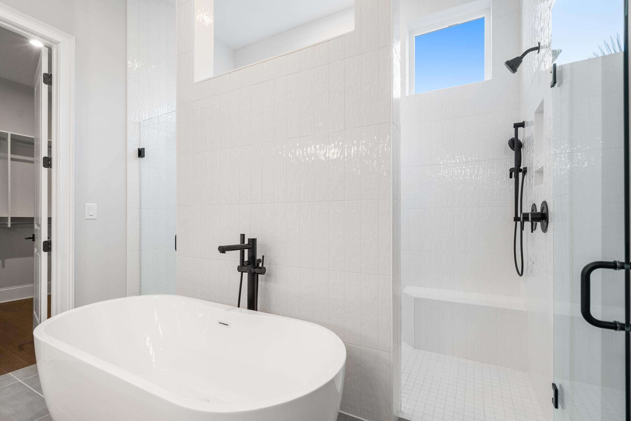 Luxurious master bathroom in The Seaside featuring freestanding soaking tub, glass walk-in shower, white subway tiles, black fixtures
