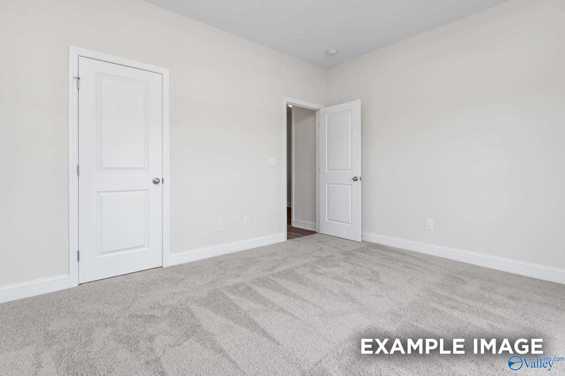 Spacious secondary bedroom with white doors, beige walls, and gray carpet in Davidson Homes The Daphne D, Arab, Alabama