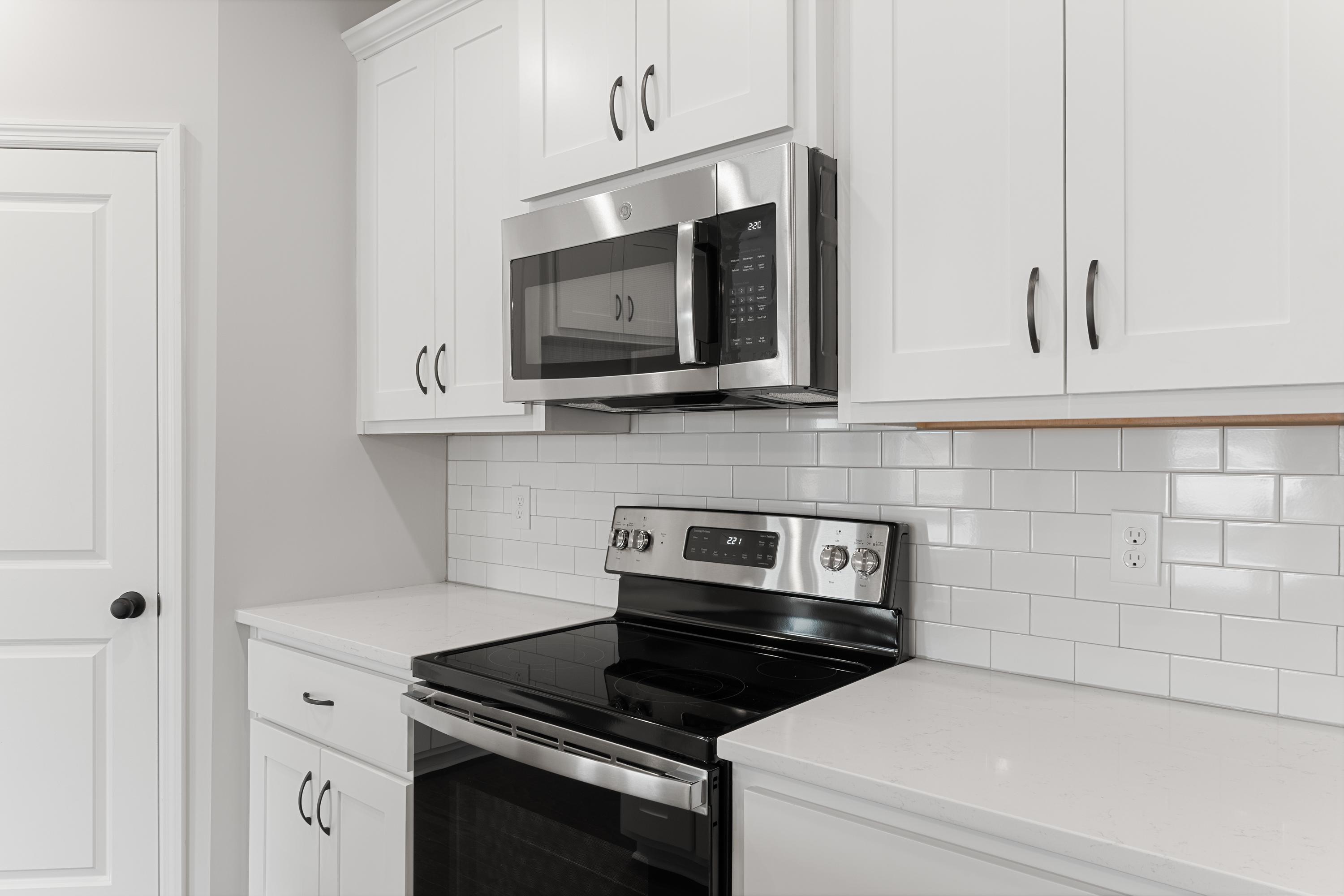 Modern Copeland kitchen by Davidson Homes featuring white shaker cabinets, stainless steel microwave, slide-in range, and subway tile backsplash