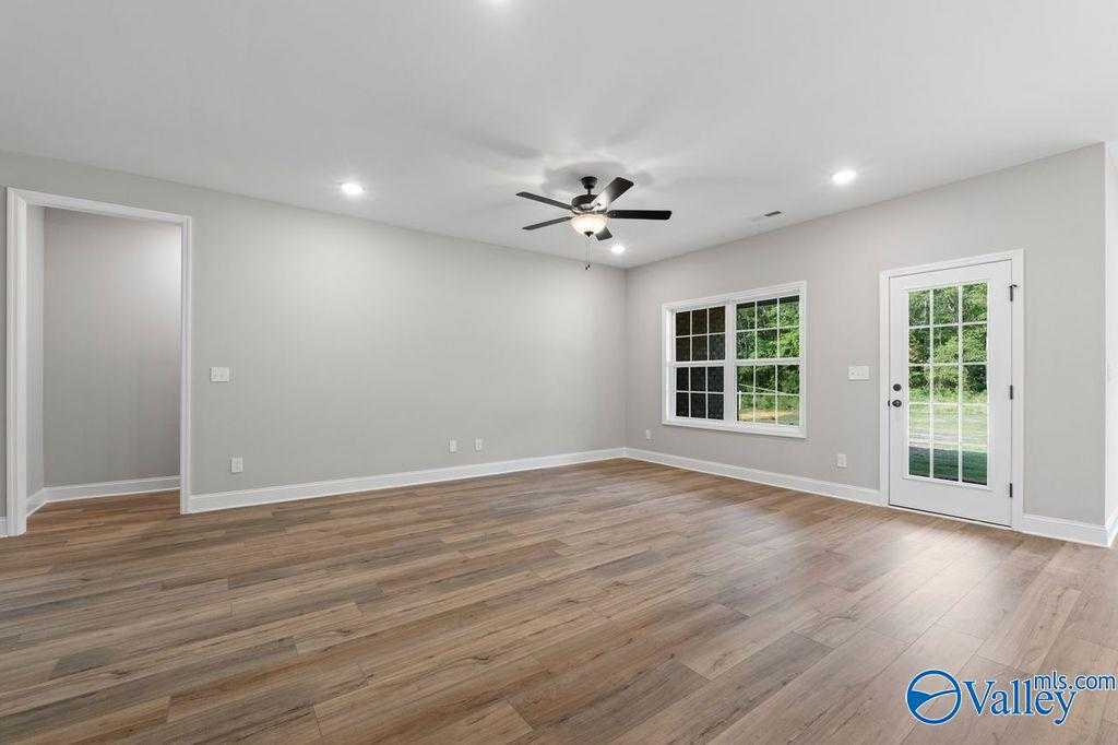 Spacious living room with hardwood floors, ceiling fan, and large windows in Davidson Homes The Montgomery B, Hartselle, Alabama