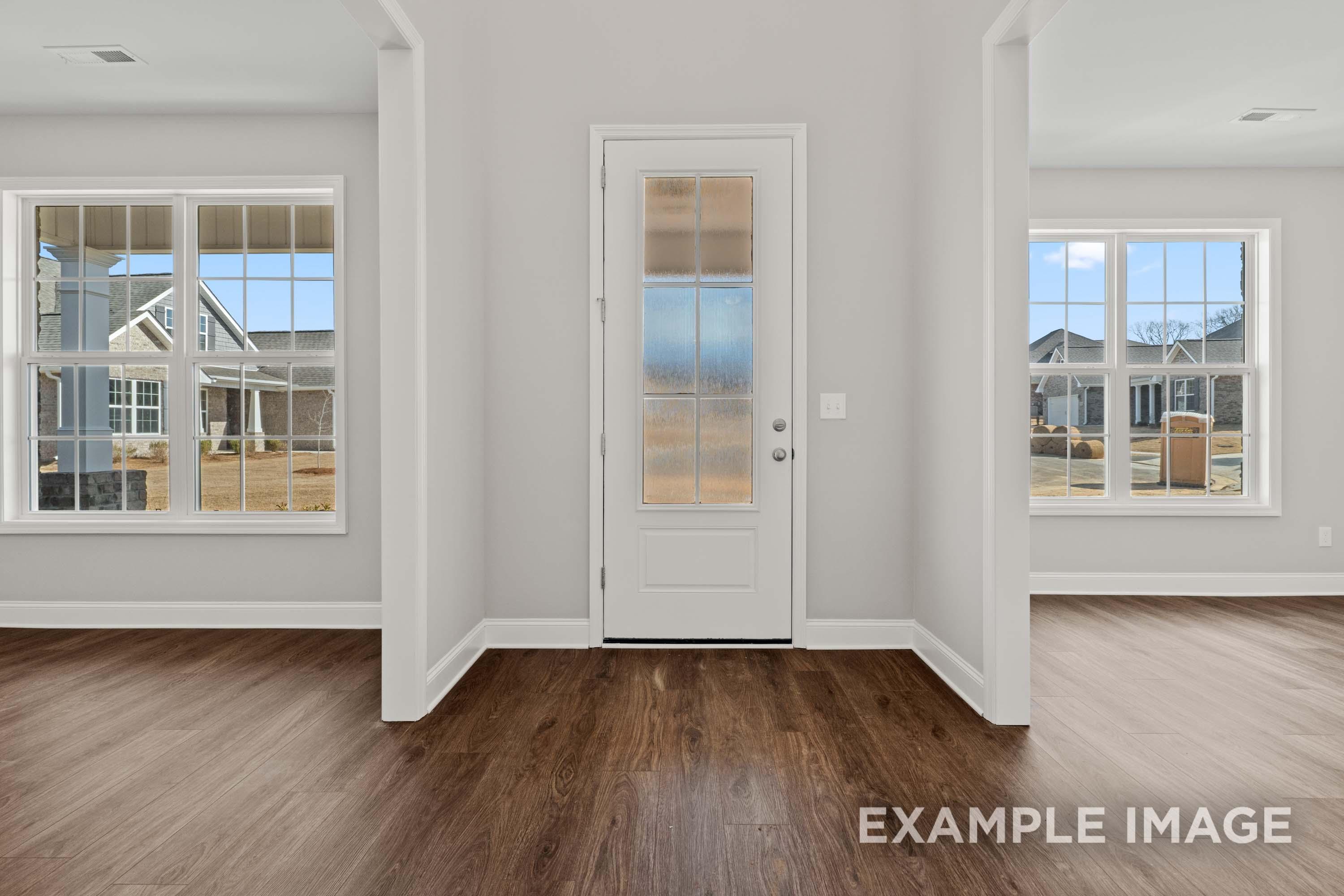 Bright hallway in The Madison B with gray walls, hardwood floors, large windows, and frosted glass door