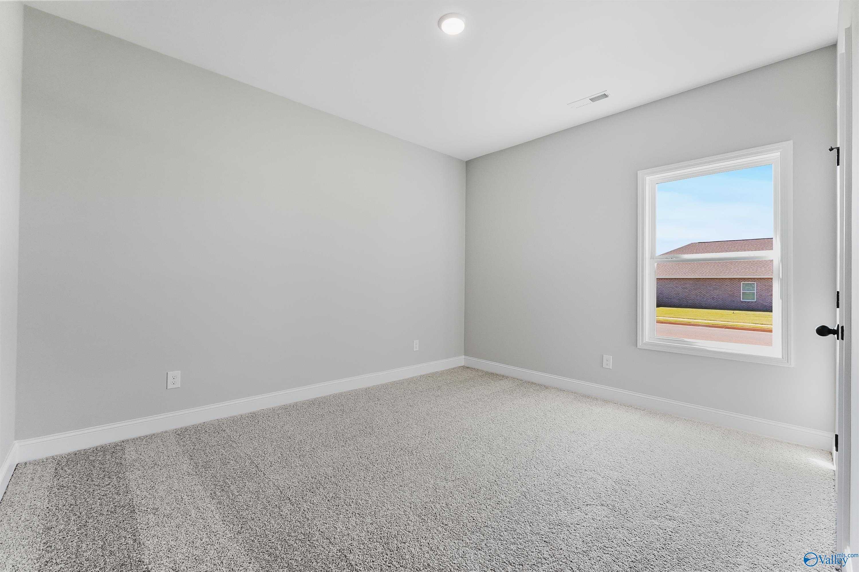 Bright secondary bedroom with gray walls, beige carpet, and window view in Davidson Homes The Daphne C, Hazel Green, AL