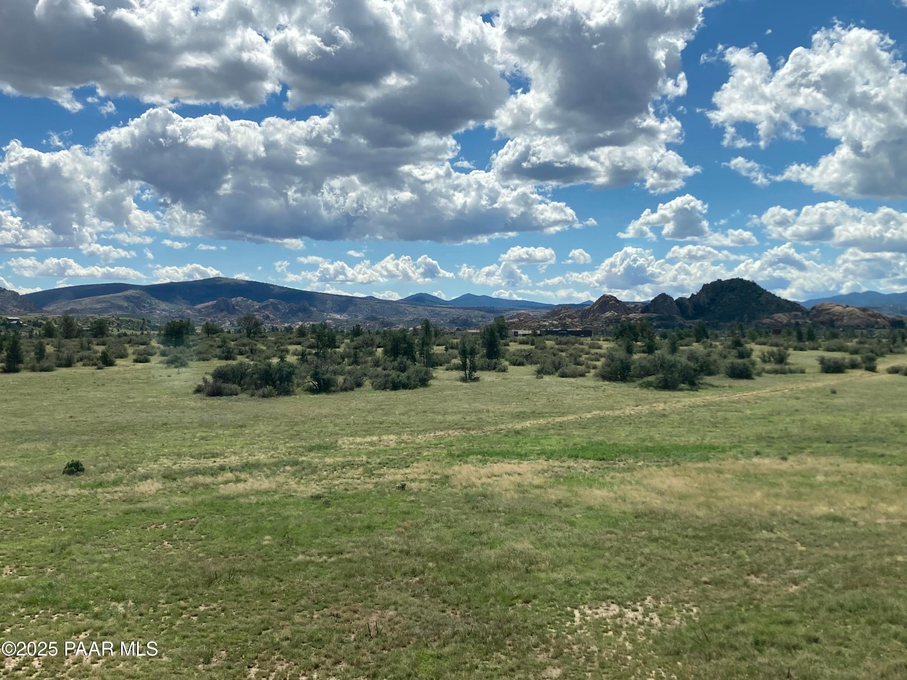 Scenic Prescott Arizona landscape with rugged mountains, lush green grasslands, scattered shrubs and partly cloudy skies in South Ranch Southern Collection