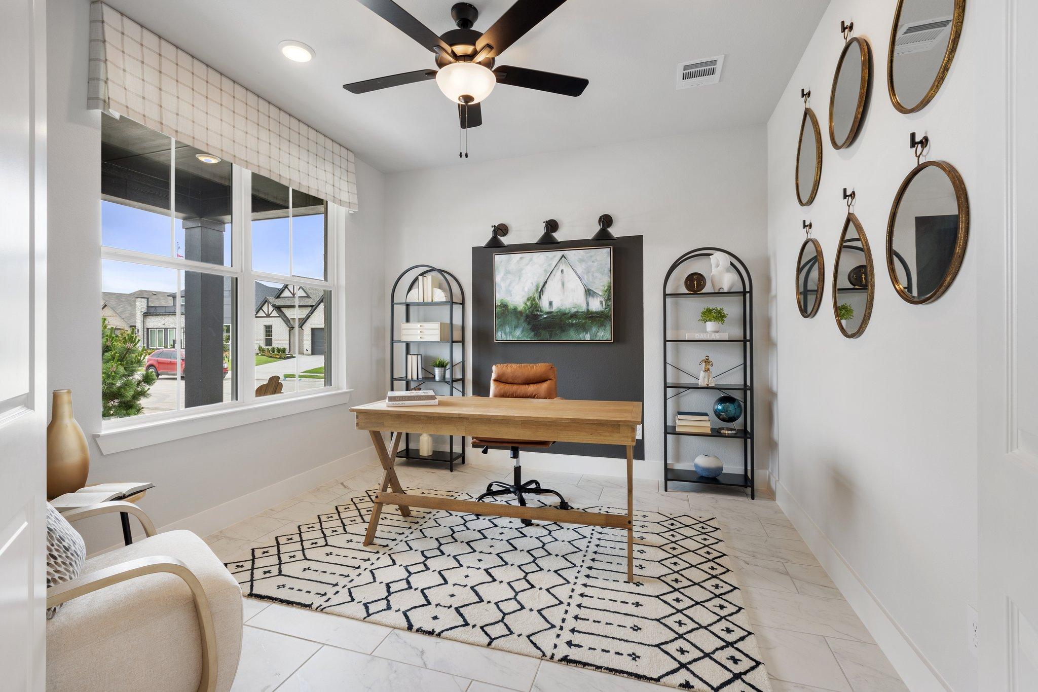 Spacious home office at Mercer Meadows in Royse City Texas with wooden desk, leather chair, ceiling fan, and wall mirrors