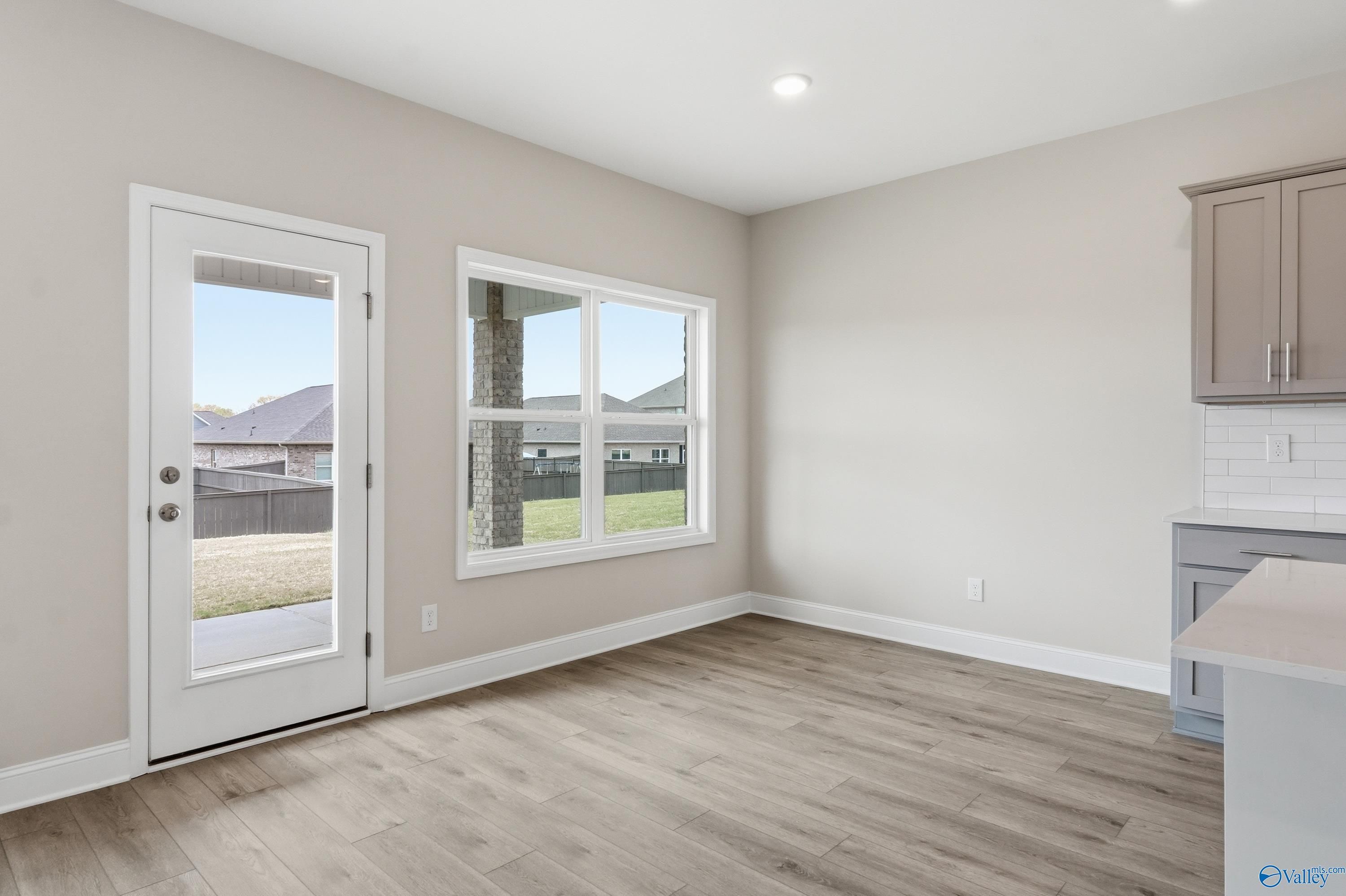 Bright breakfast nook with sliding glass doors to grassy backyard, beige cabinets, and hardwood floors in The Shelby B home, New Market, Alabama