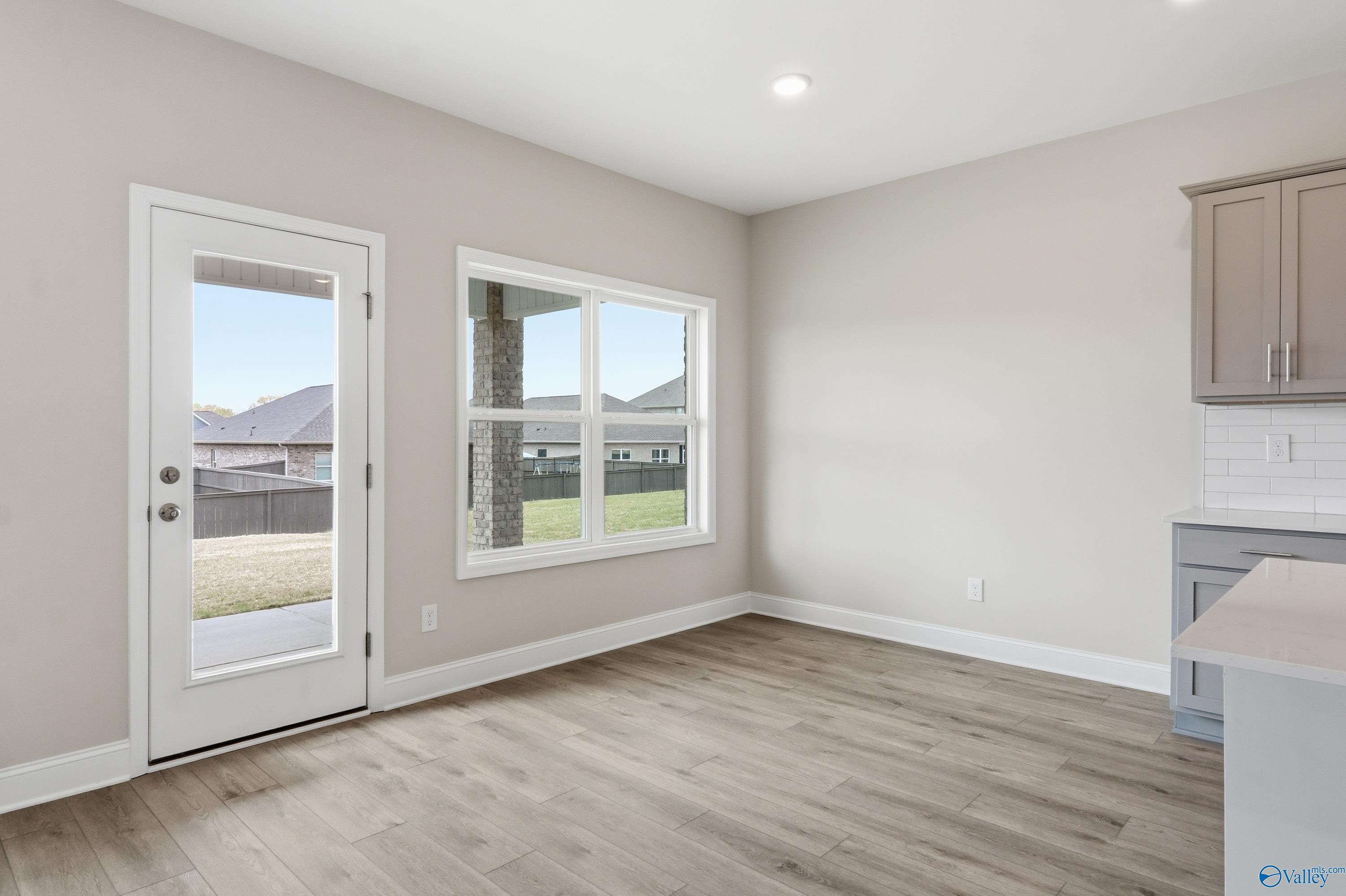 Bright breakfast nook with sliding glass doors to grassy backyard, beige cabinets, and hardwood floors in The Shelby B home, New Market, Alabama