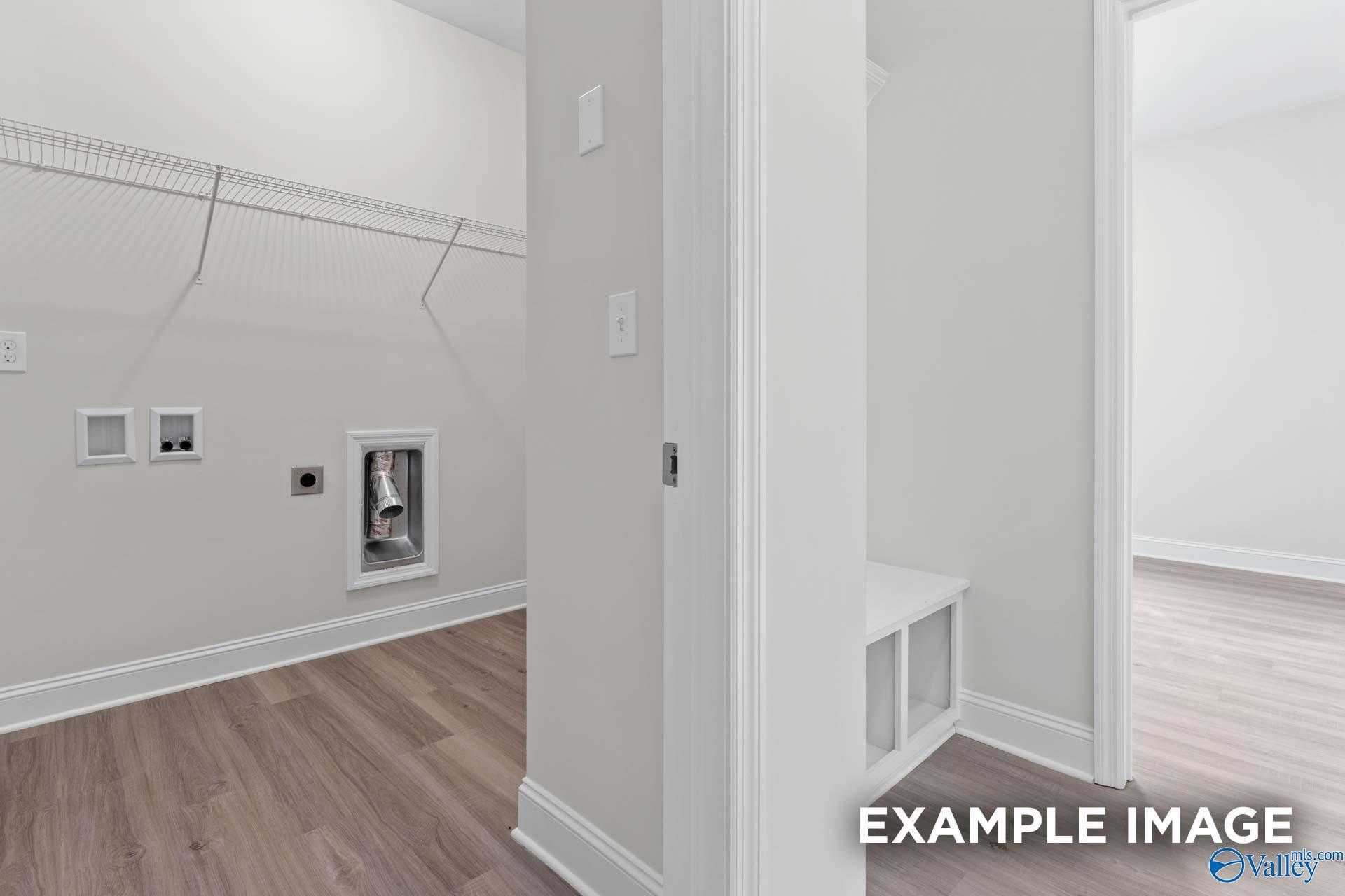 Spacious laundry room with wire shelving closet, washer dryer hookups, and built-in bench in Davidson Homes The Daphne D, Arab, Alabama