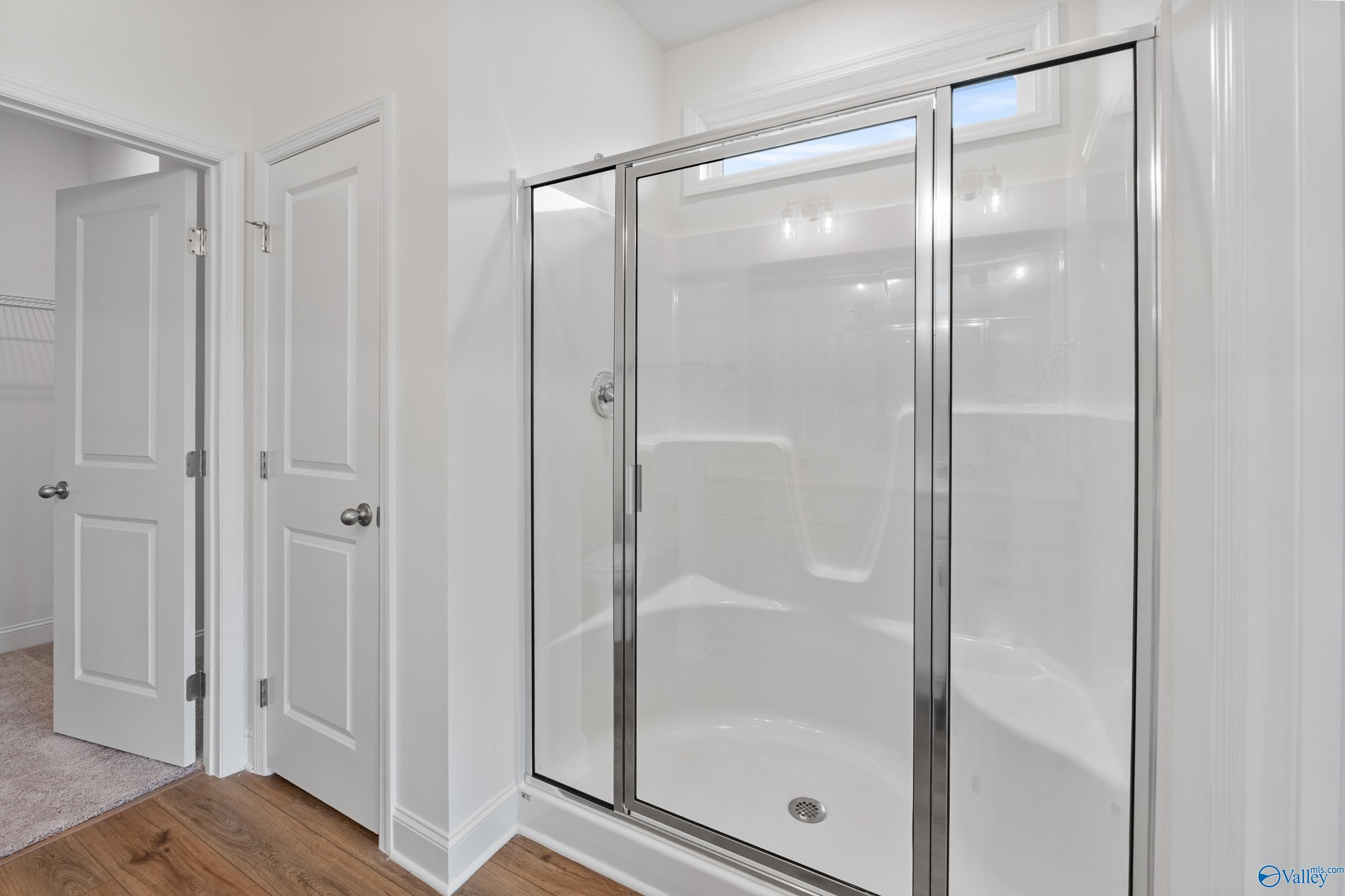 Modern glass-enclosed walk-in shower with white subway tiles in master bathroom of Davidson Homes The Asheville C, New Market, Alabama