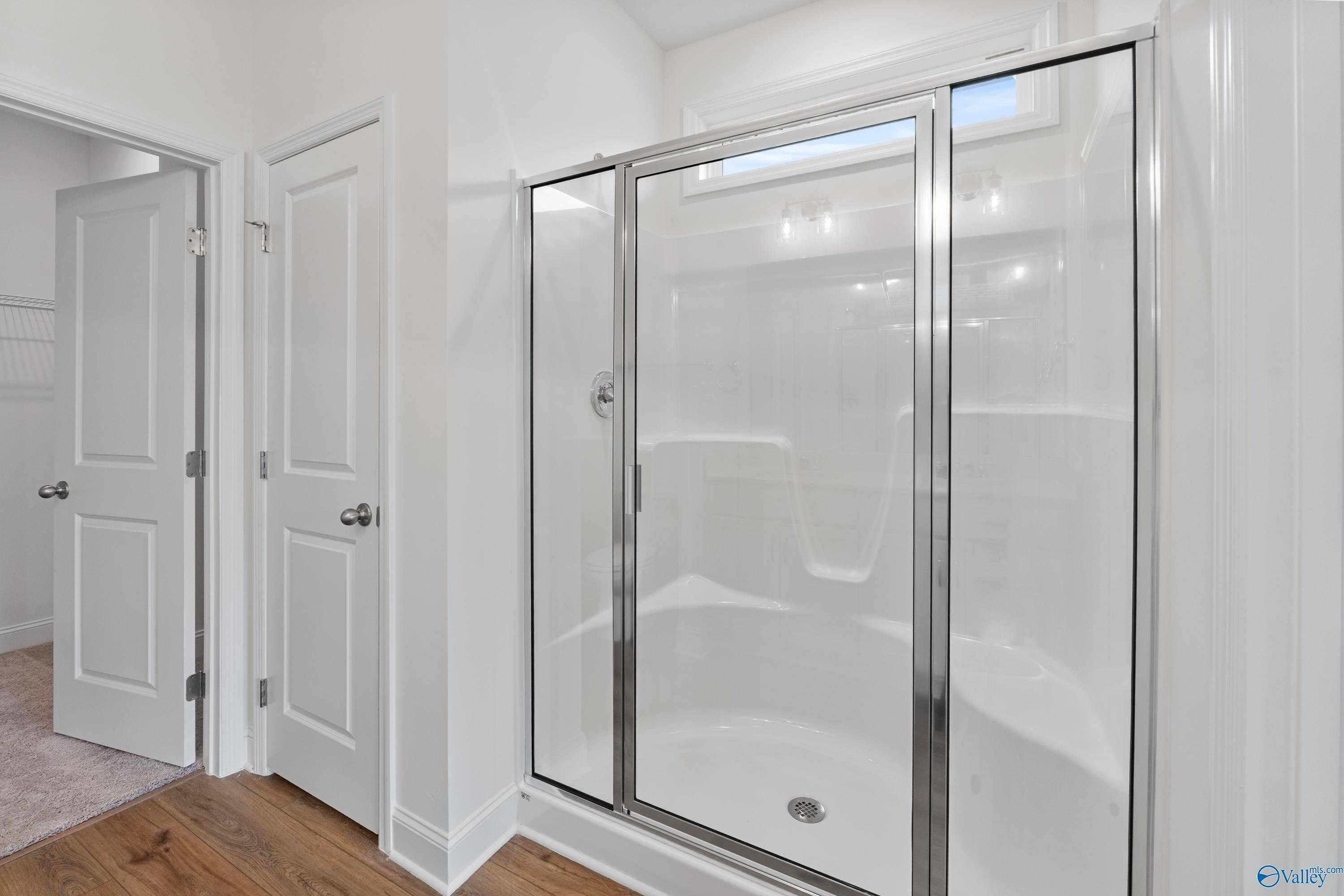 Modern glass-enclosed walk-in shower with white subway tiles in master bathroom of Davidson Homes The Asheville C, New Market, Alabama