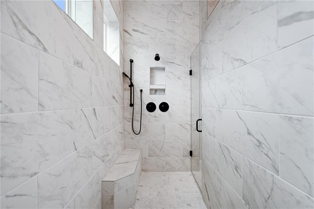 Luxurious white marble walk-in shower with rain head, glass doors, and built-in bench in master bath, Davidson Homes The Seaside B, Woodstock, GA