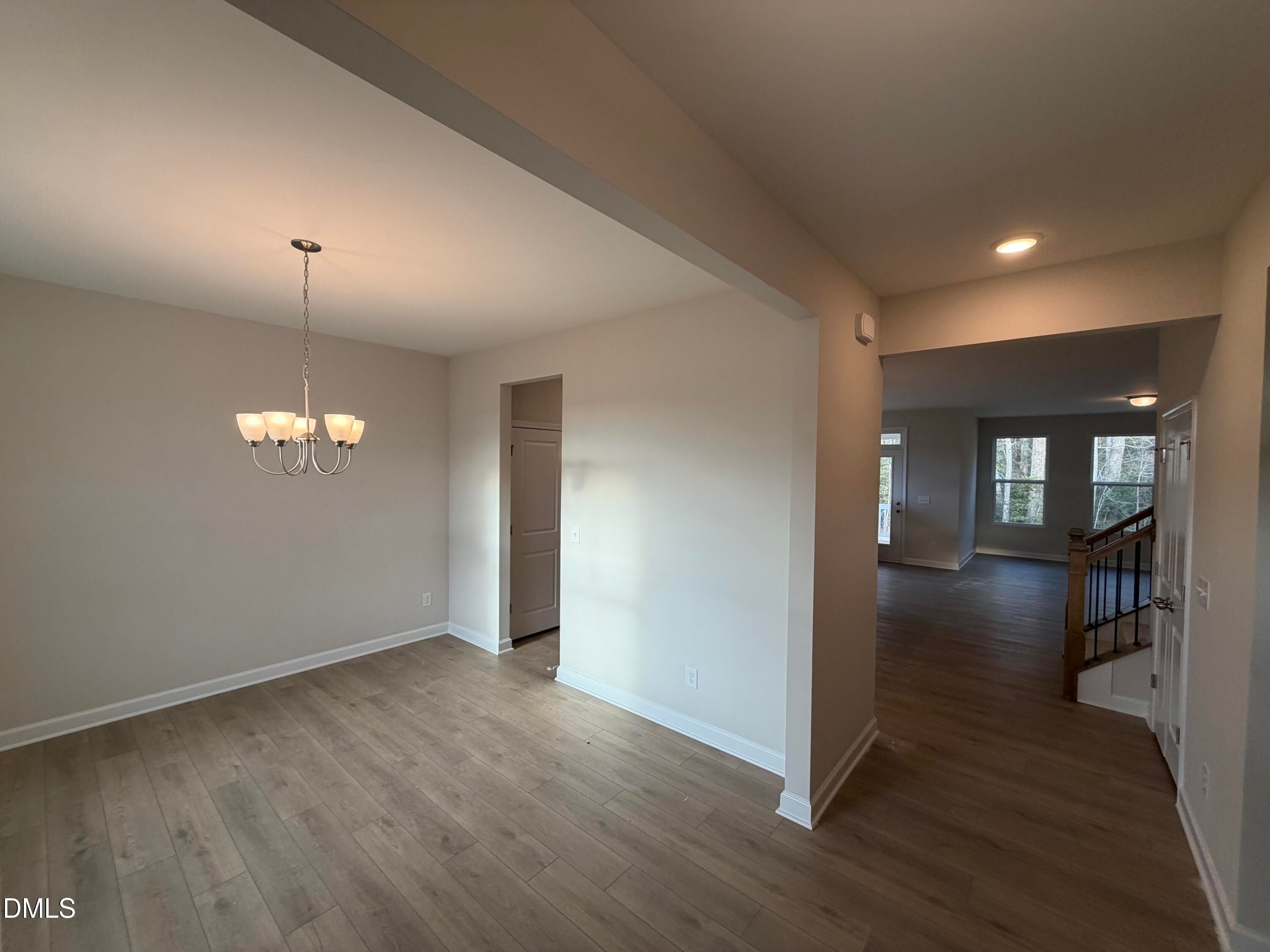 Elegant formal dining room with crystal chandelier, hardwood floors, and open archway to staircase in Davidson Homes The Ash B, Lillington, NC