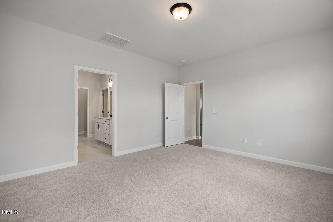 Spacious carpeted bedroom with an ensuite bathroom in The Birch II A floor plan at Montrose in Aberdeen, North Carolina.